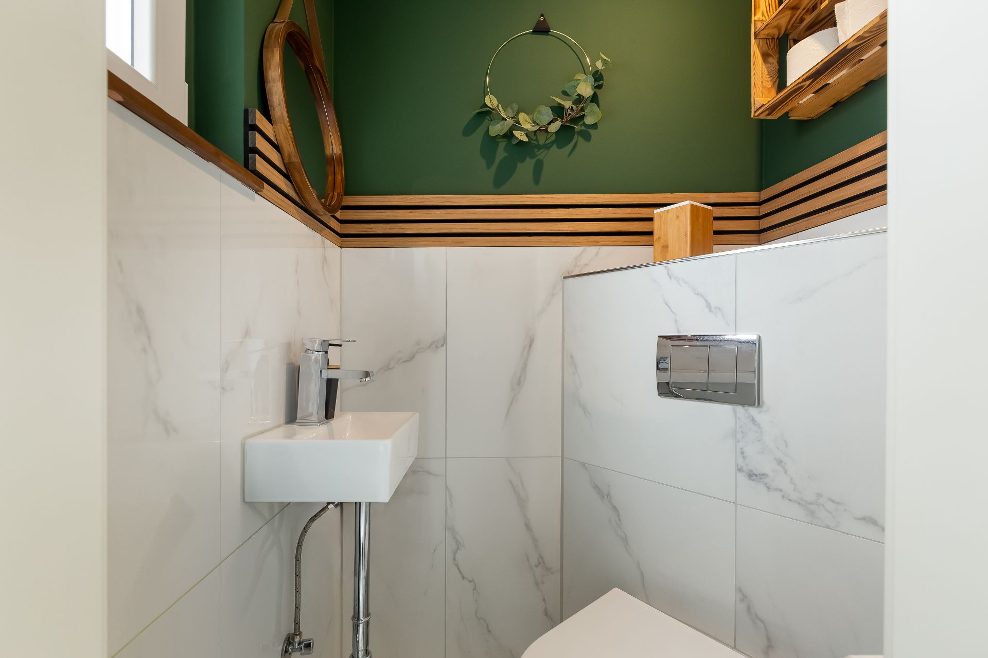 Kleines Badezimmer mit Wandtoilette, kleinem Waschbecken und moderner Dekoration.