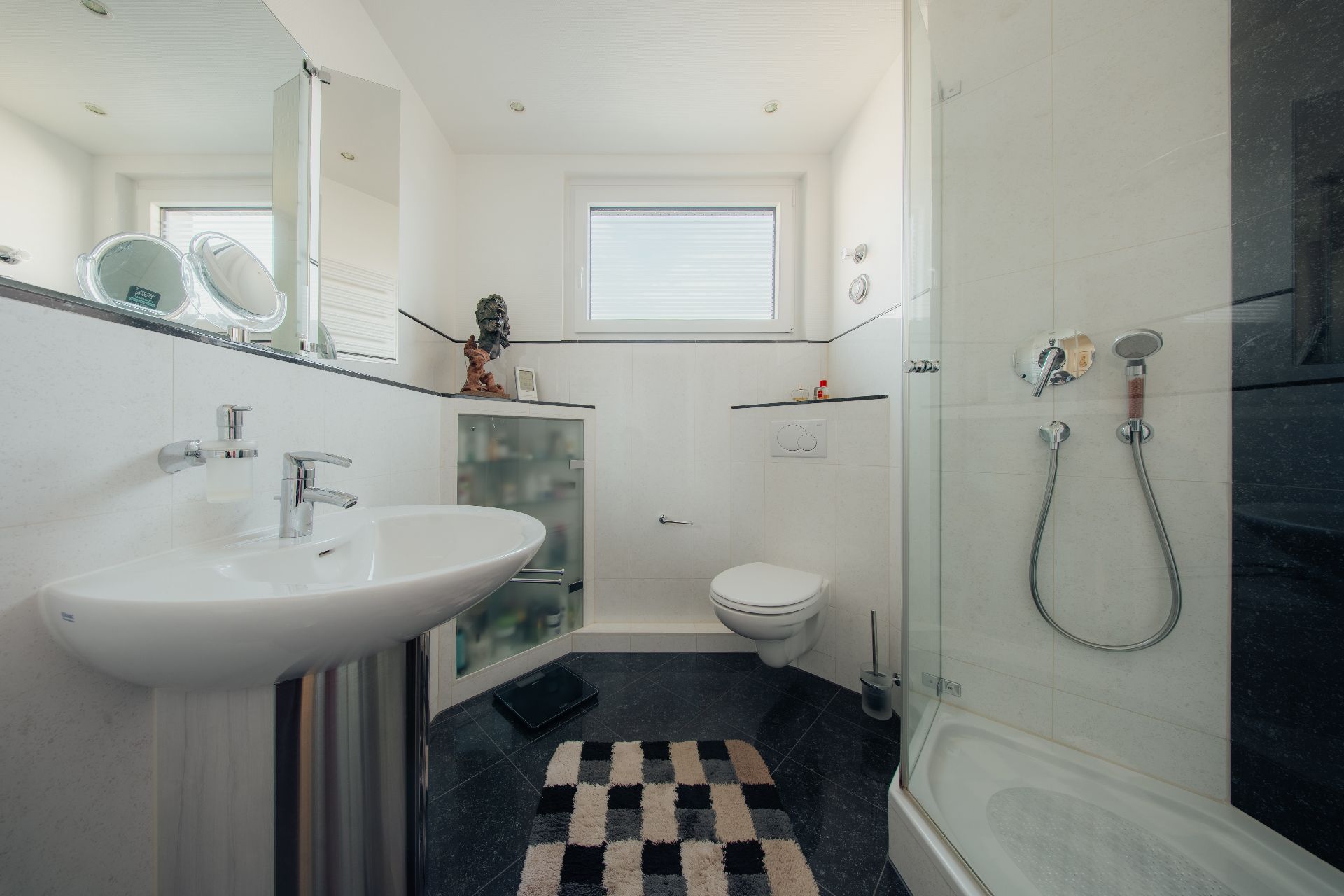 Modernes Bad mit Waschbecken, Toilette, Dusche und Schrank, Fenster an der Rückwand.