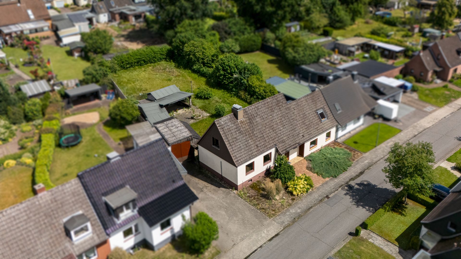 Luftaufnahme eines Einfamilienhauses mit Garten in einer Wohnsiedlung.