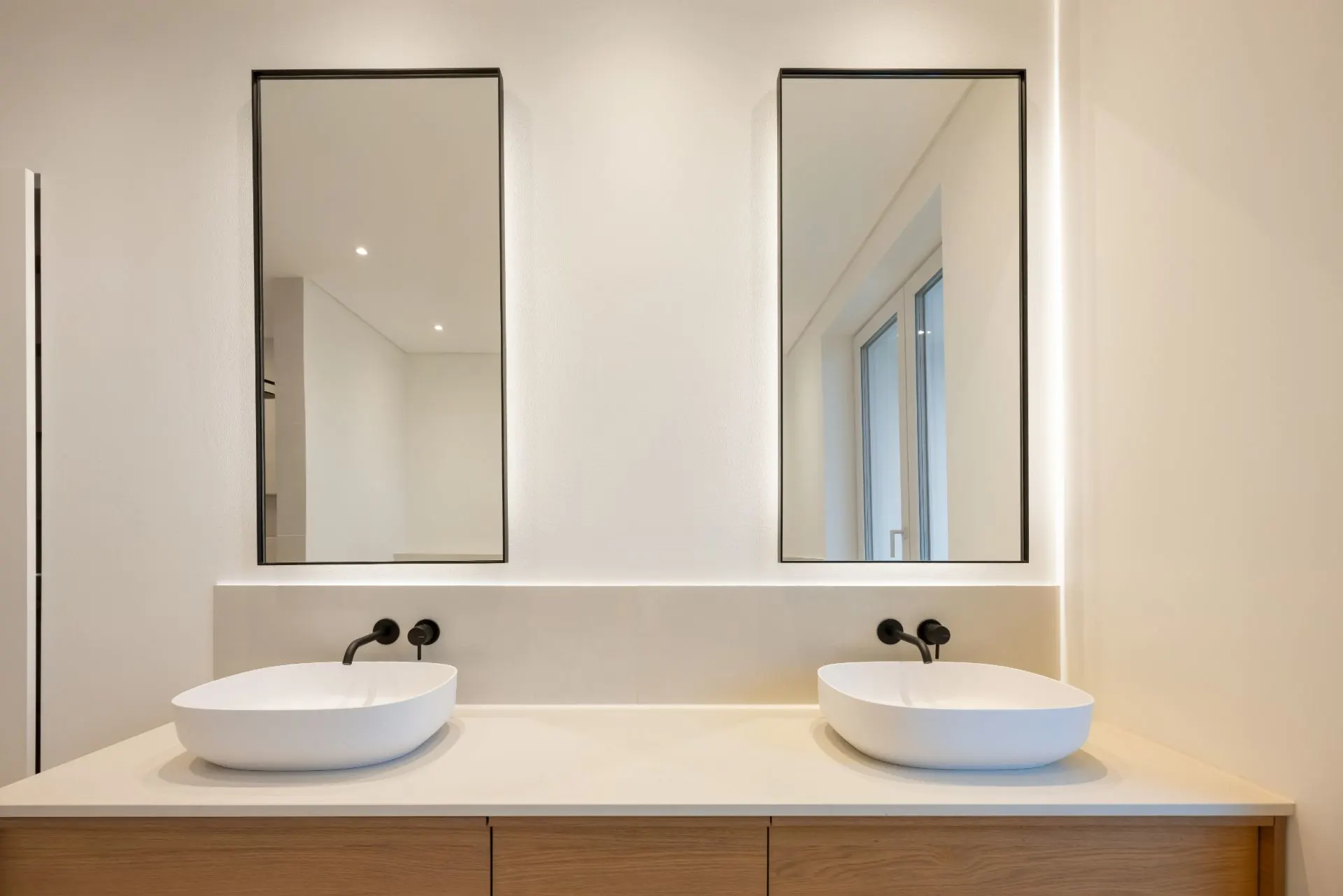Modernes Badezimmer mit zwei Waschbecken und zwei rechteckigen Spiegeln.