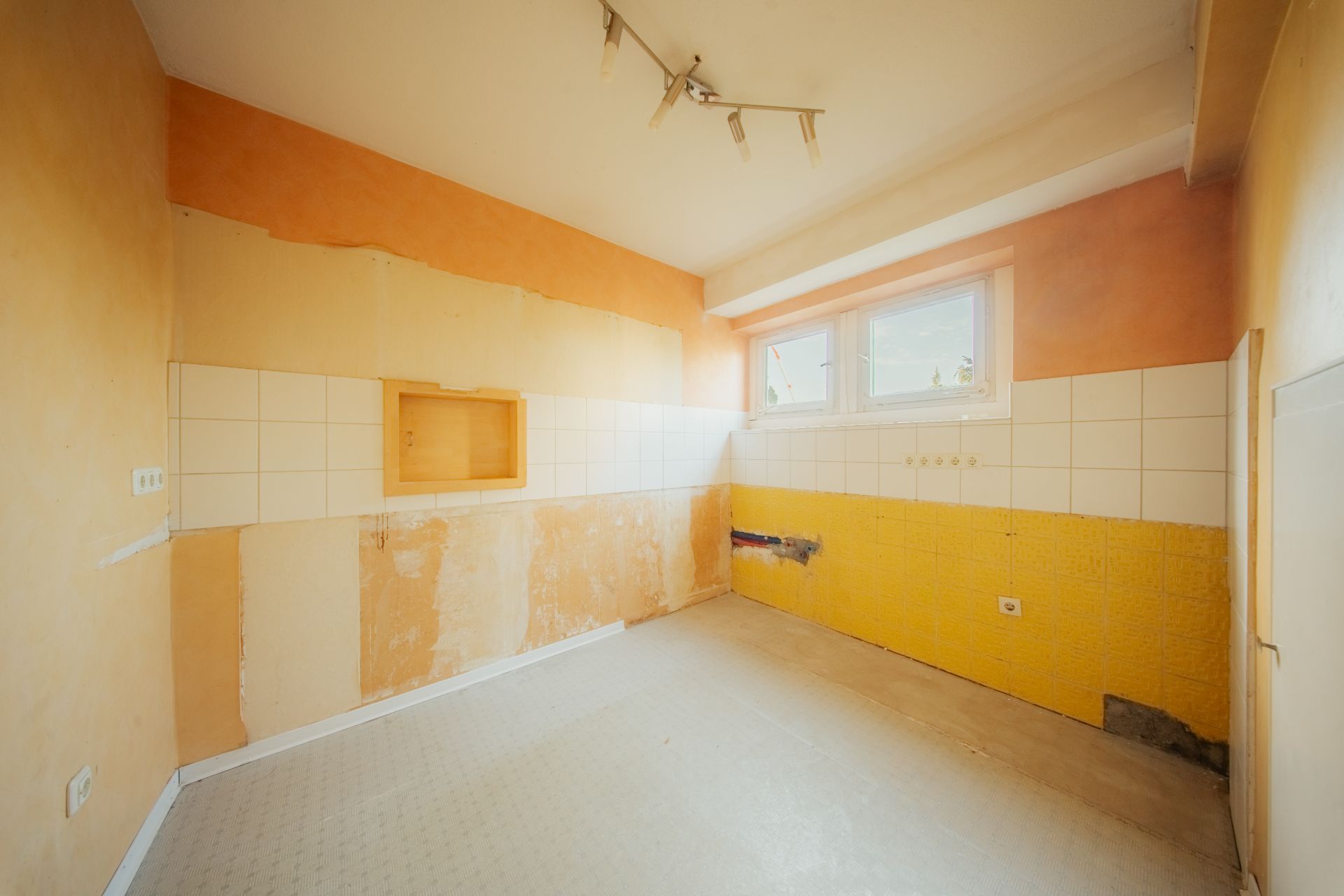 Leerer Raum mit gefliester Wand, gelber Farbe und großem Fenster.