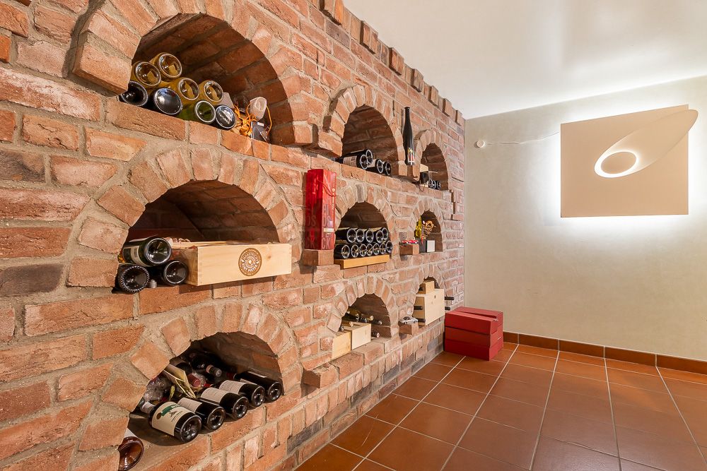 Weinkeller mit gemauerter Wand und eingelassenen Regalen für Weinflaschen.
