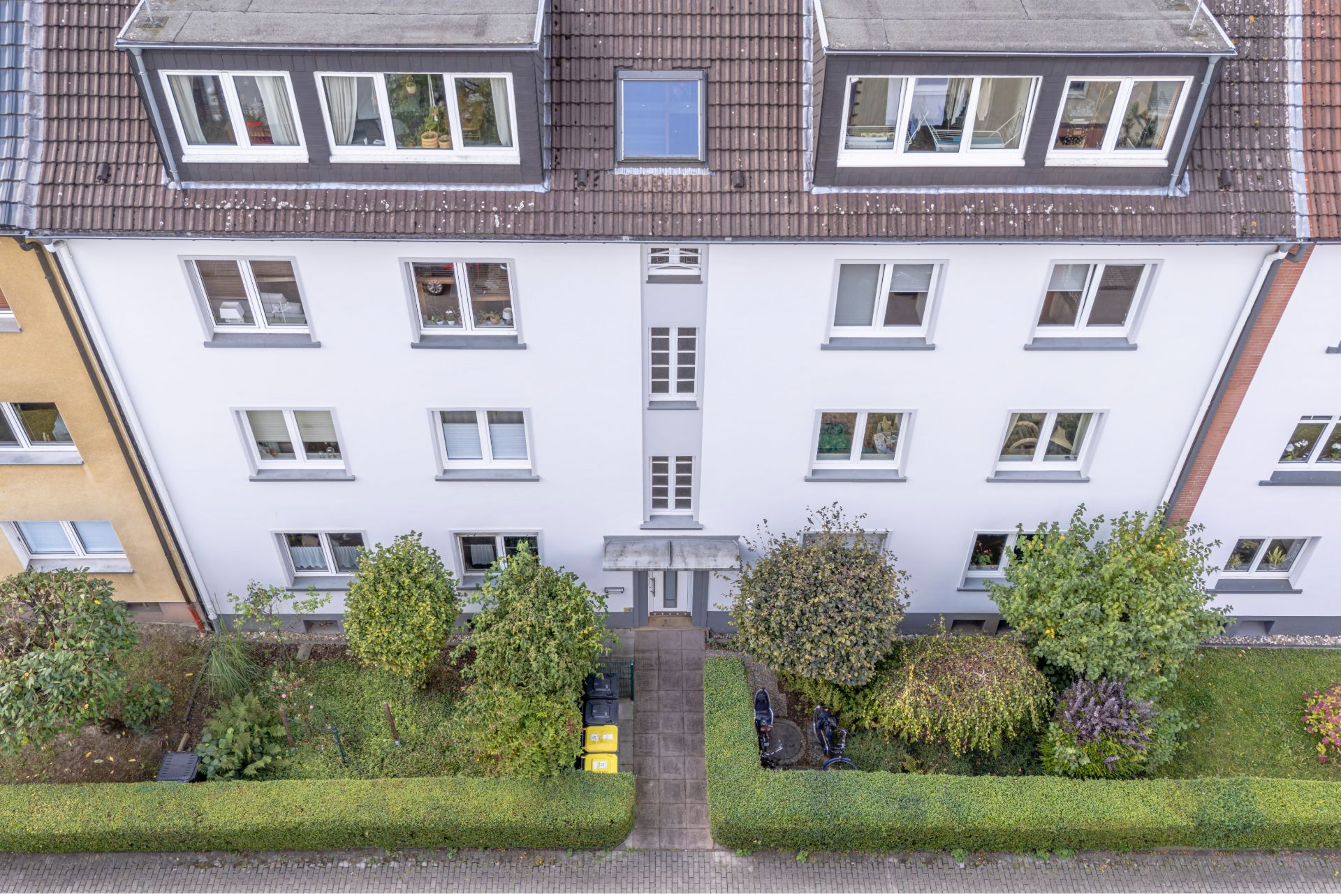 Vorderseite eines Wohnhauses mit mehreren Fenstern und gepflegtem Vorgarten.