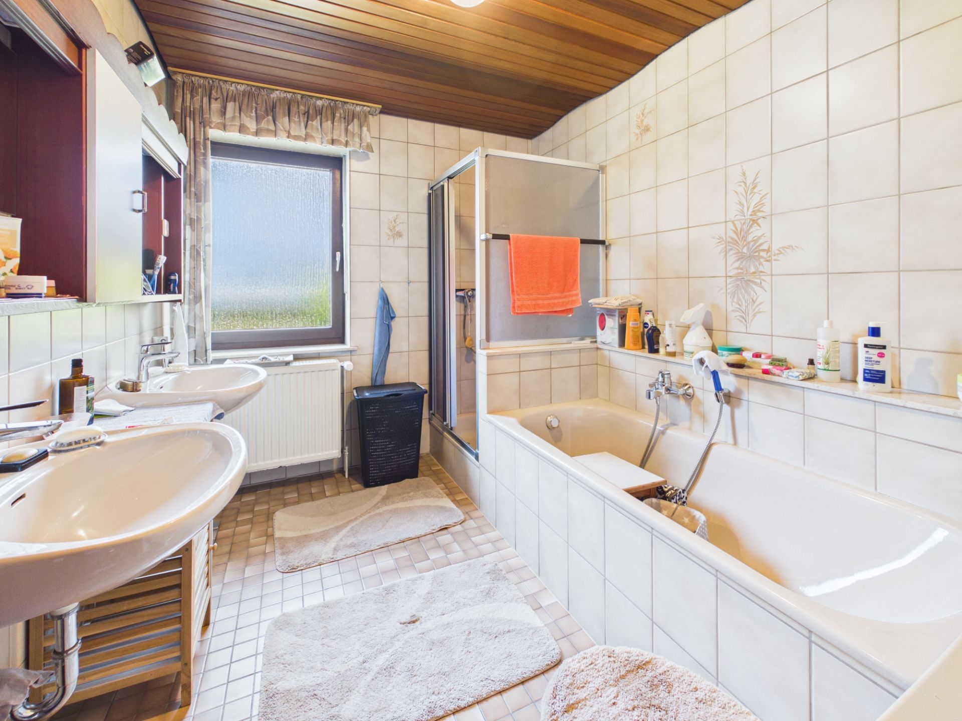 Badezimmer mit zwei Waschbecken, Badewanne, Dusche und Fenster.