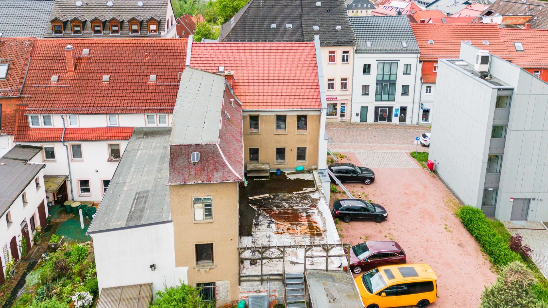 Mehrere Wohnhäuser mit Innenhof und parkenden Autos, von oben aufgenommen.