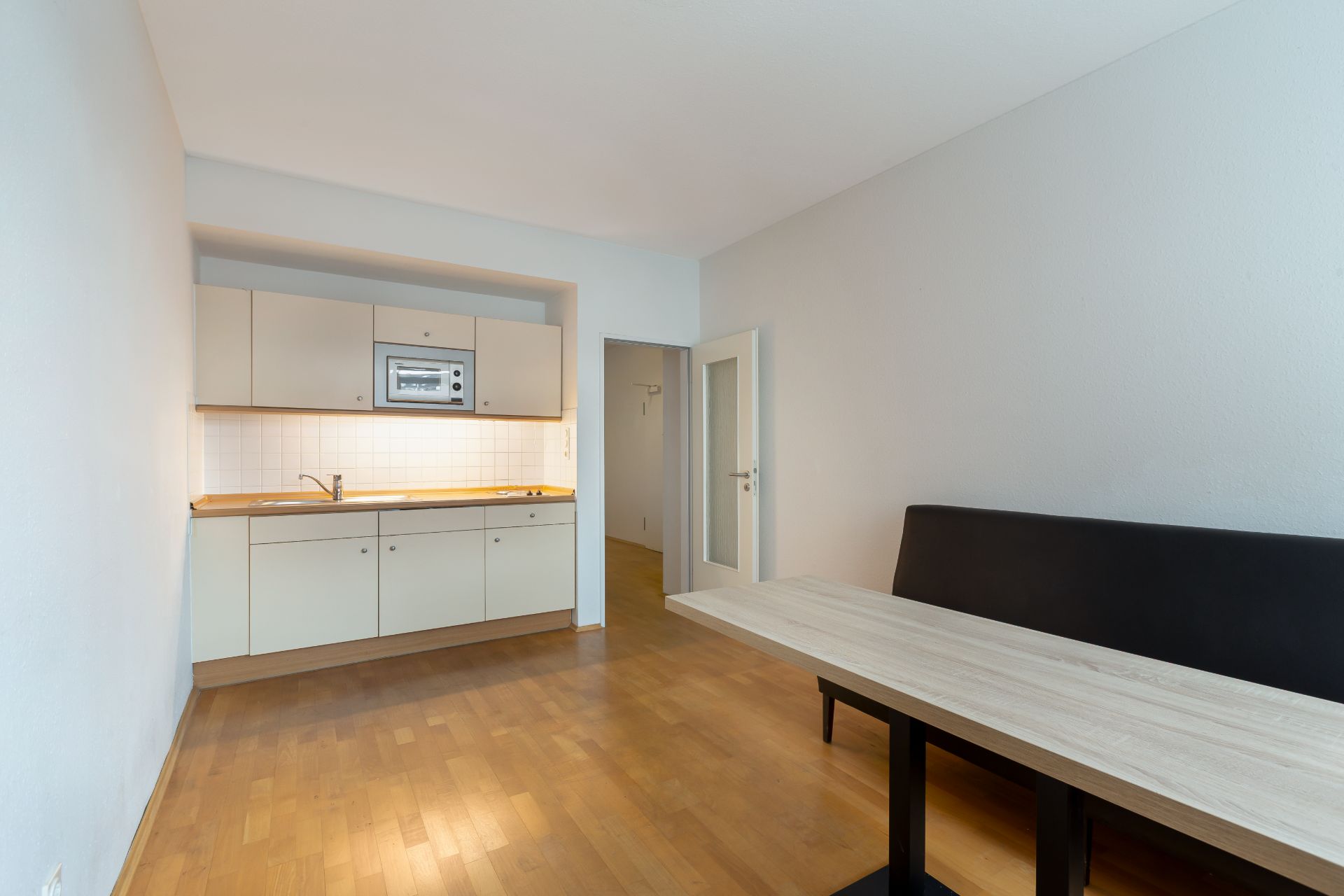 Wohnküche mit Einbauküche, Holzboden und Esstisch mit Bank.