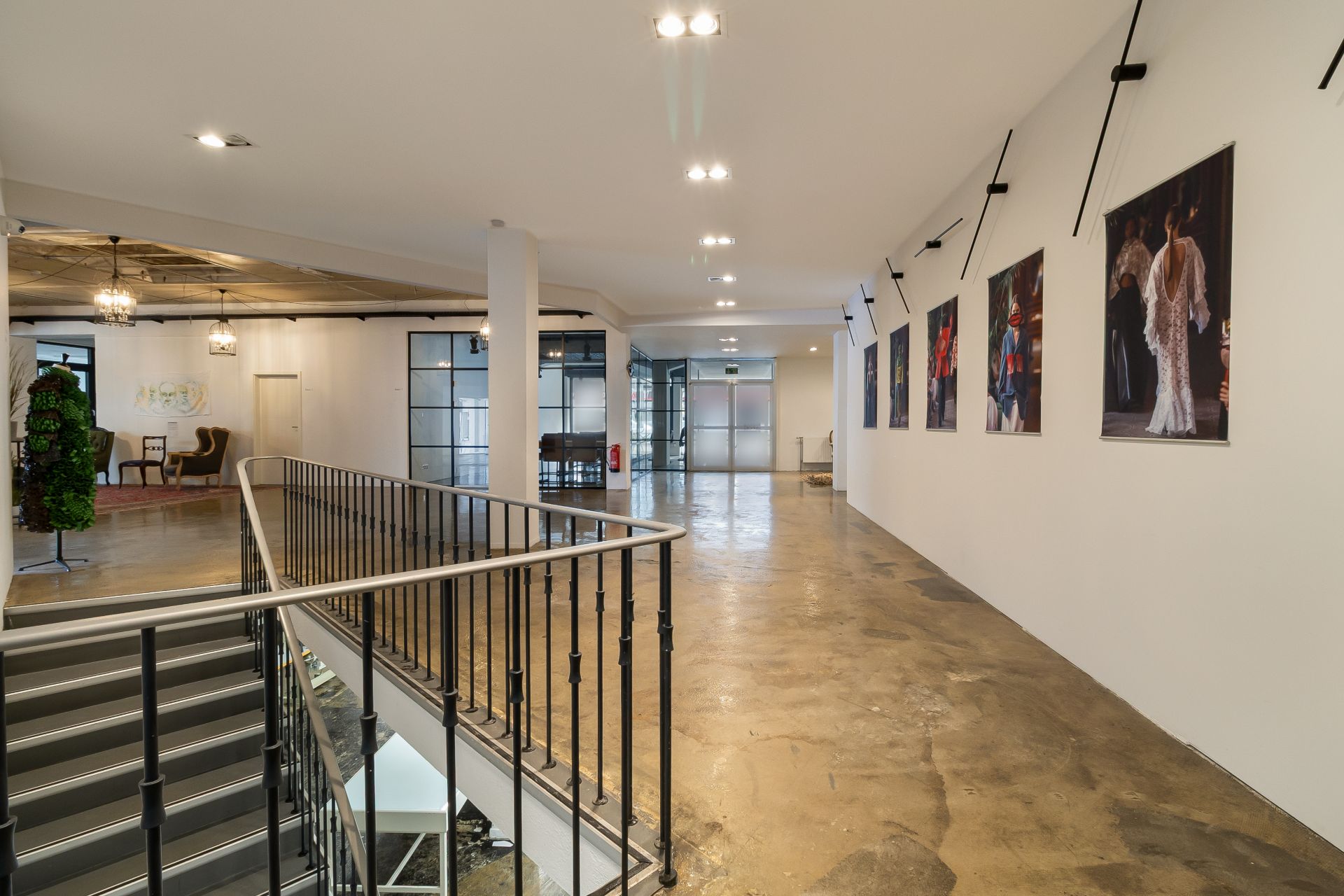 Helle Flur mit Treppe, Bildern an der Wand und Sitzbereich im Hintergrund.