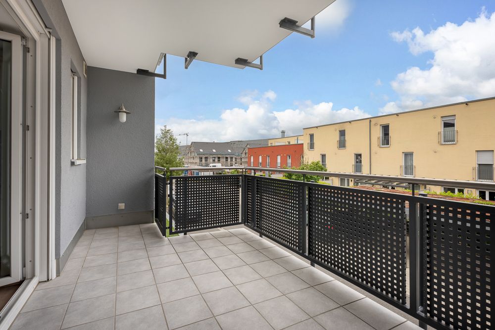 Moderner Balkon mit Fliesenboden und Metallgeländer, Blick auf Nachbargebäude.