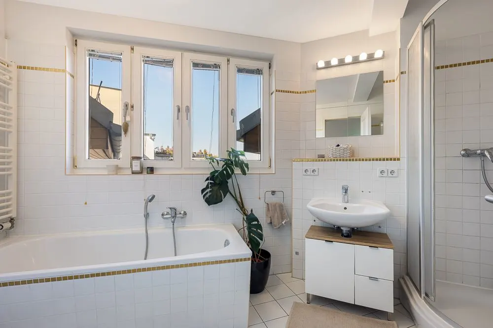 Modernes Badezimmer mit Badewanne, Dusche, Waschbecken, Spiegel und großem Fenster.