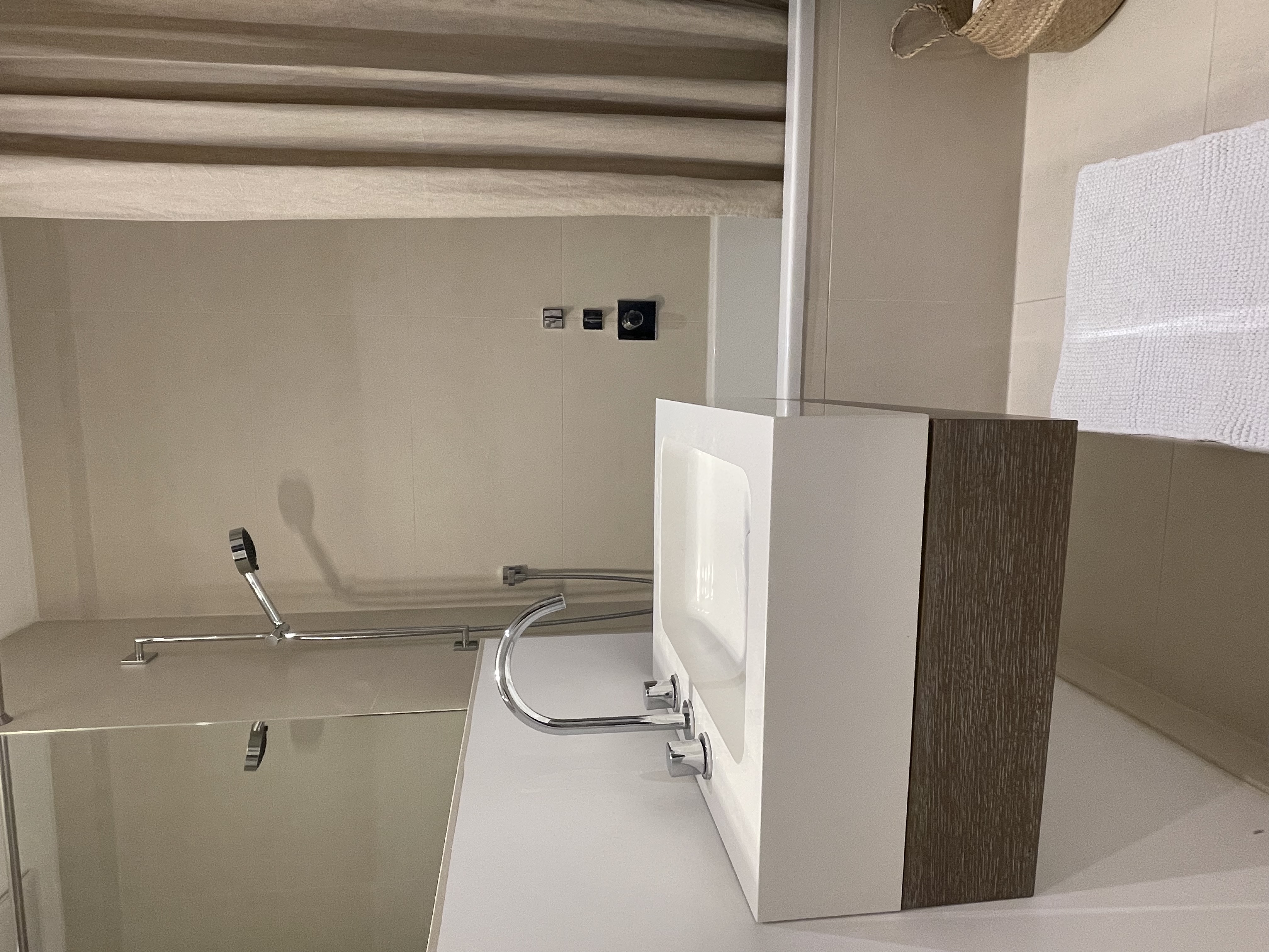 Modernes Badezimmer mit Waschbecken, Badewanne, Duschkopf und hellem Duschvorhang.