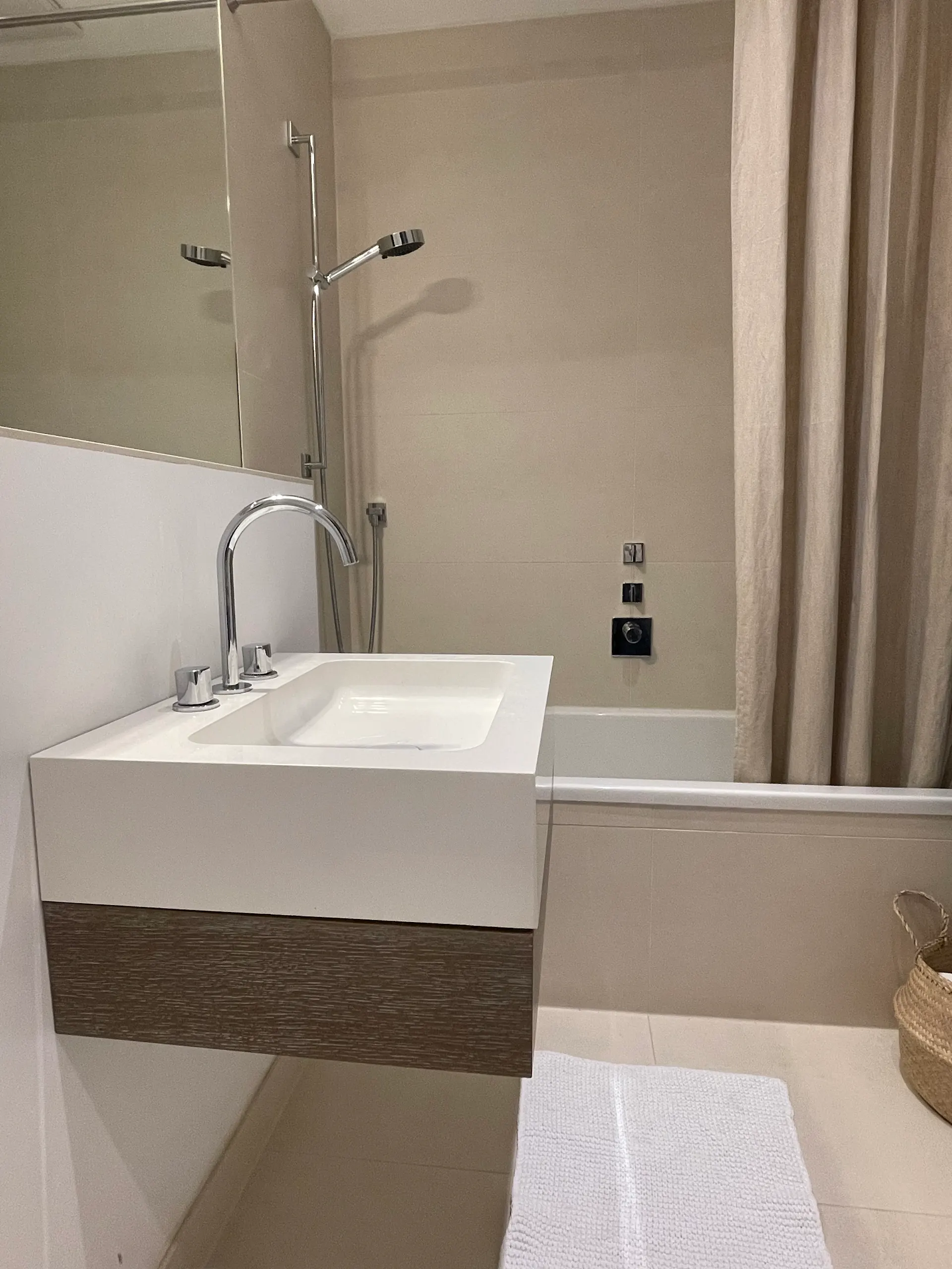 Modernes Badezimmer mit Waschbecken, Badewanne, Duschkopf und hellem Duschvorhang.
