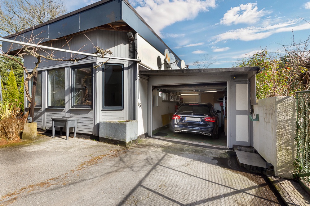 Außenansicht eines Wohnhauses mit angebauter Garage, in der ein Auto parkt.