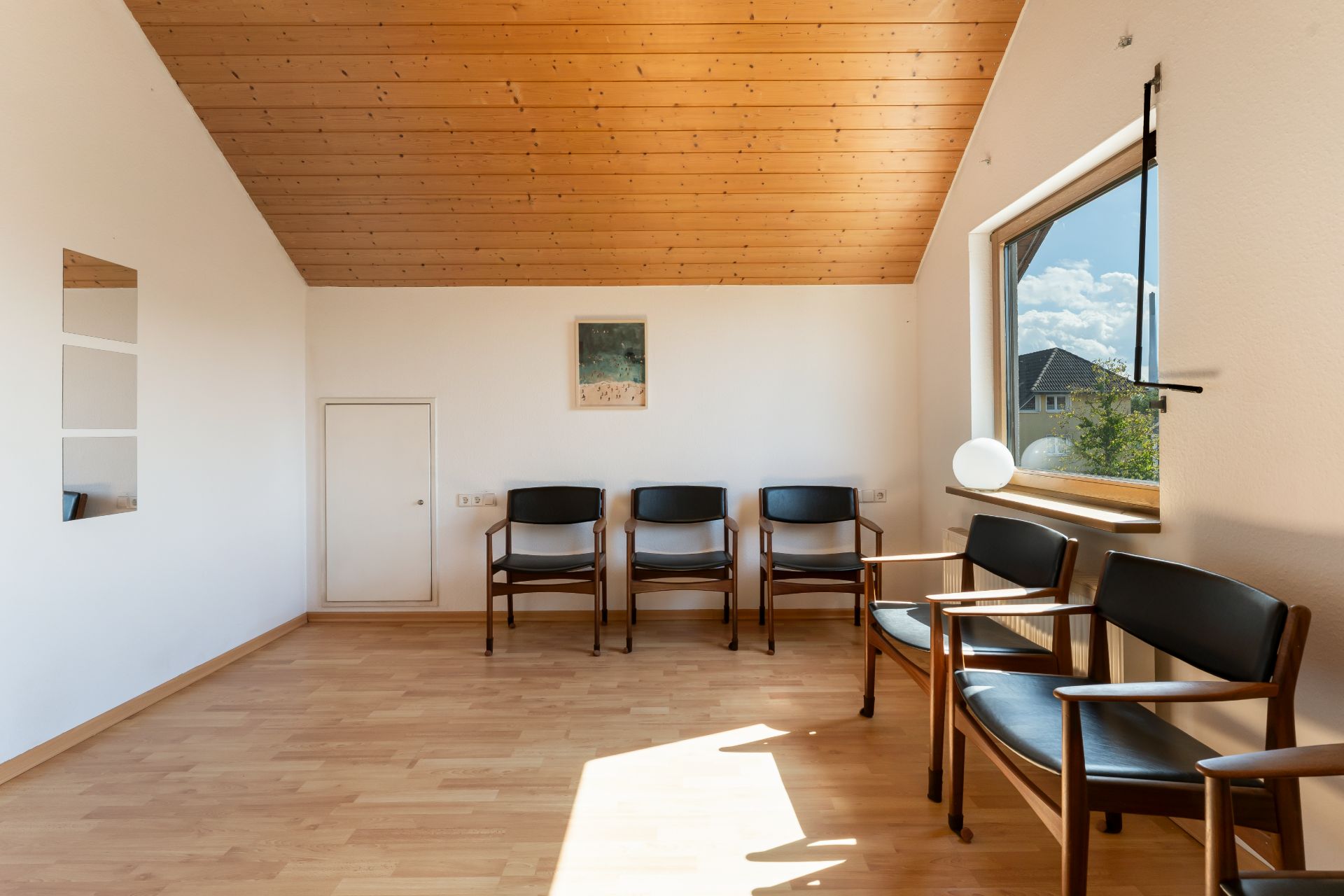 Heller Raum mit Holzdecke, sechs Stühlen, Bild an der Wand und großem Fenster.