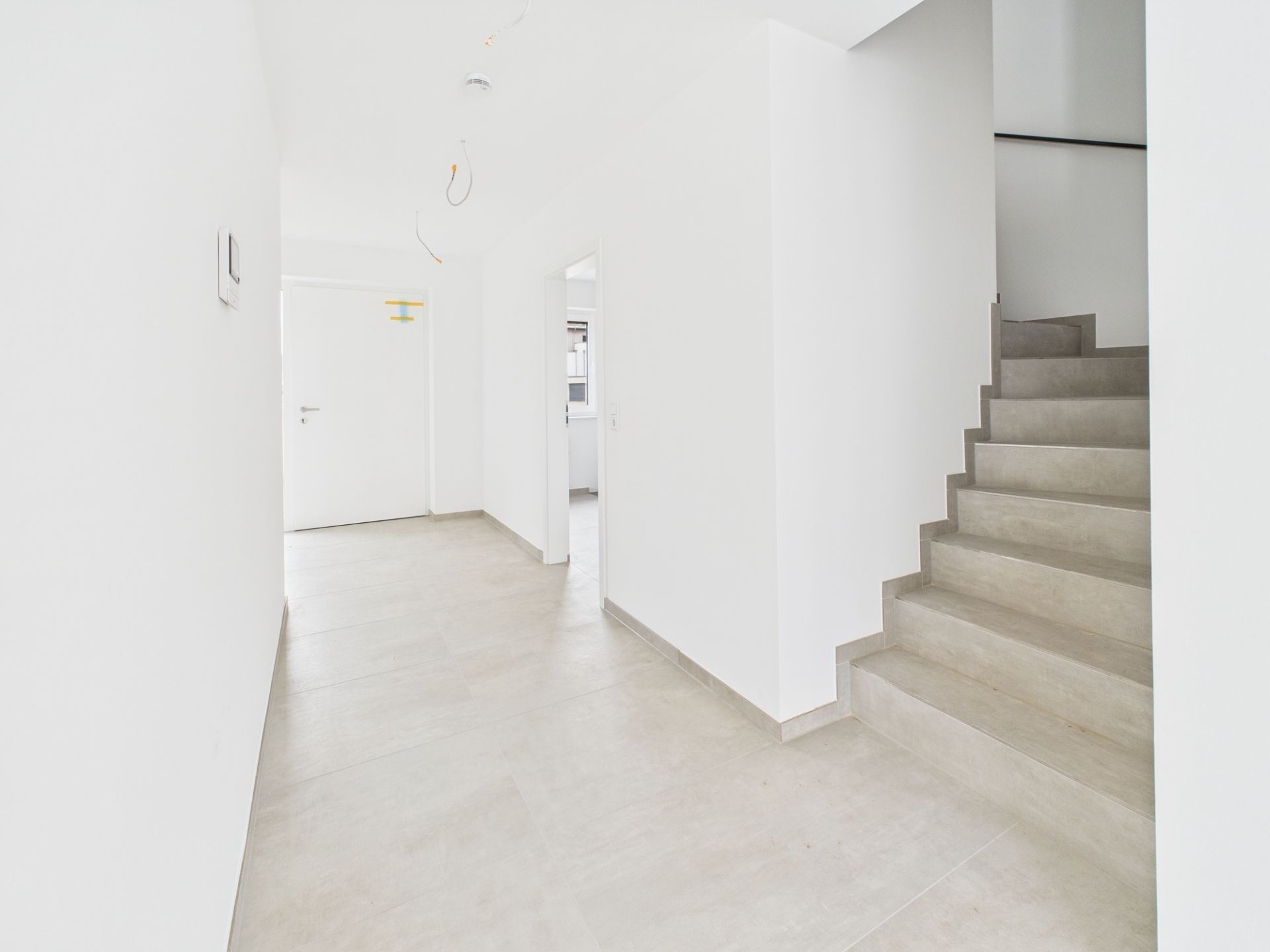 Heller Flur mit beigen Fliesen und Treppe nach oben in einem Wohnhaus.