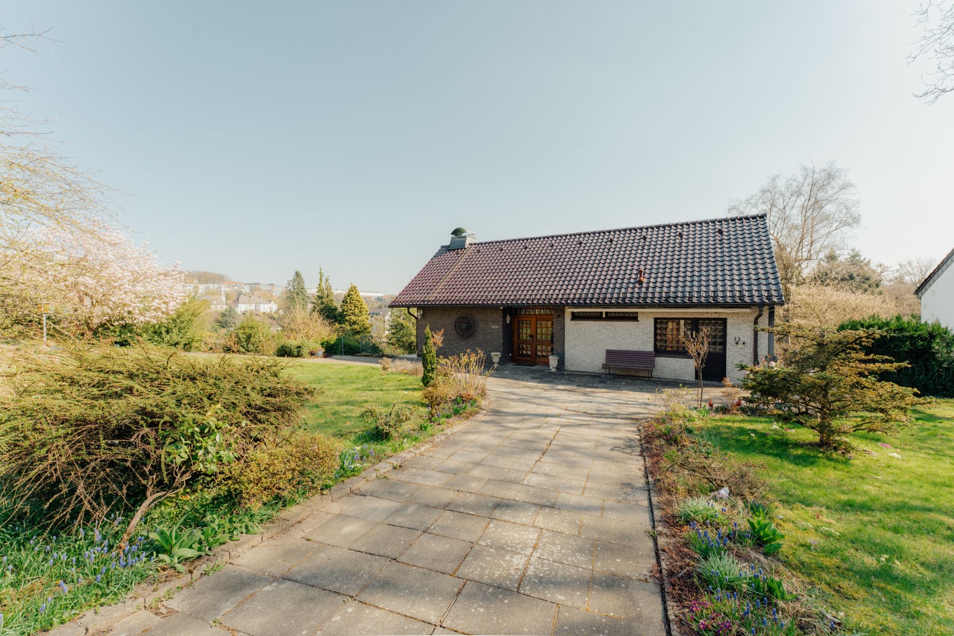 Einfamilienhaus mit gepflastertem Weg und großem Garten im Vordergrund.