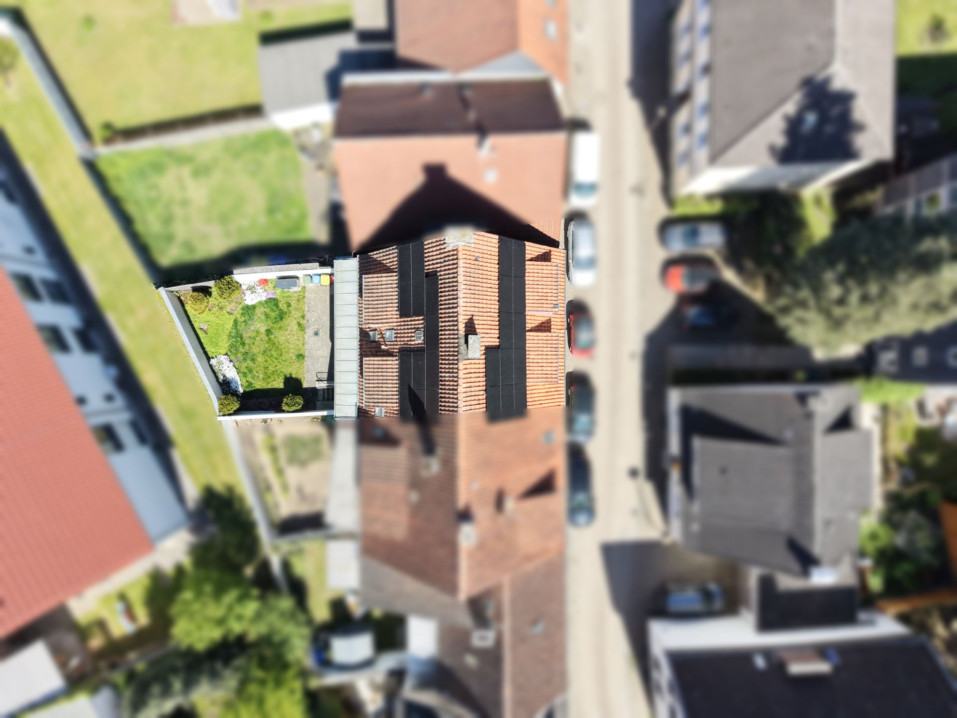 Luftaufnahme eines Hauses mit Garten und angrenzenden Gebäuden in einer Wohngegend.