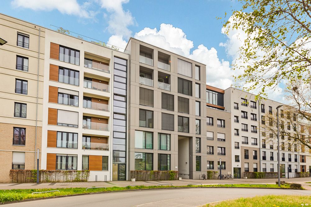 Moderne mehrstöckige Wohngebäude mit Balkonen und großen Fenstern an einer Straße.