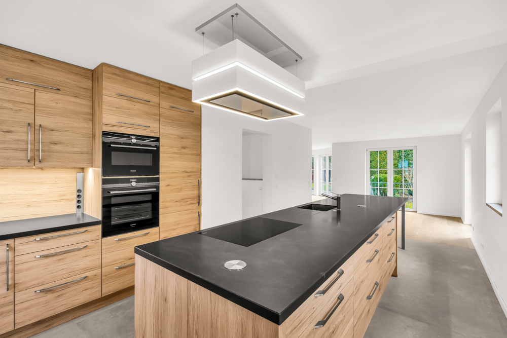 Moderne Küche mit Holzschränken, schwarzer Arbeitsplatte und großem Küchenblock.