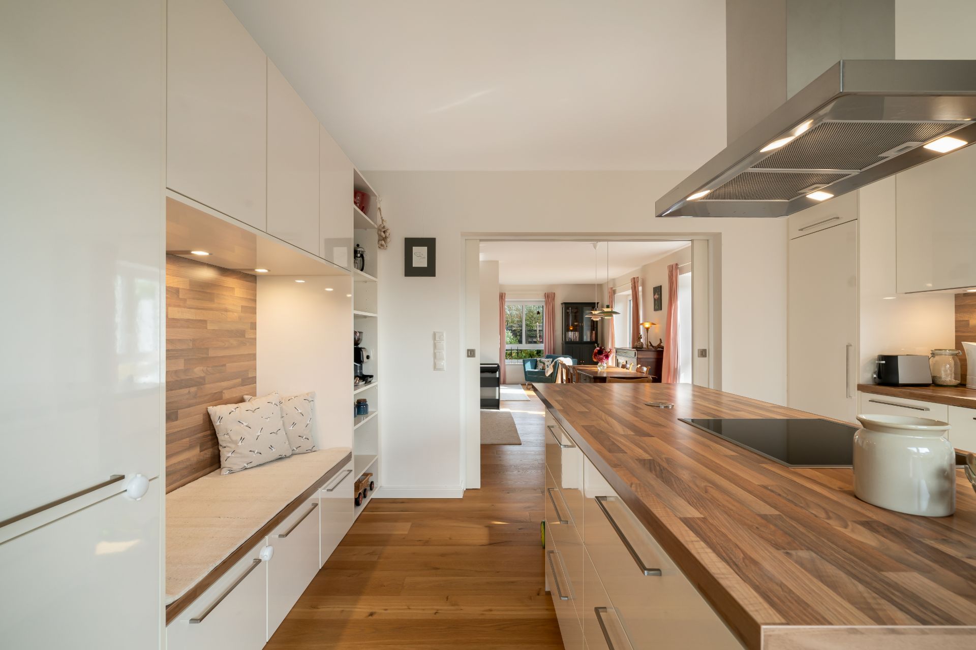 Moderne Küche mit Holzboden, Sitzbank und Blick ins Wohnzimmer.