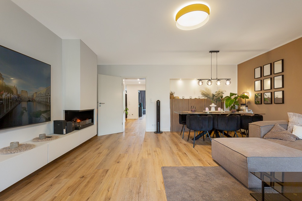 Modernes Wohnzimmer mit Sofa, Esstisch, TV, Kamin und Holzboden.