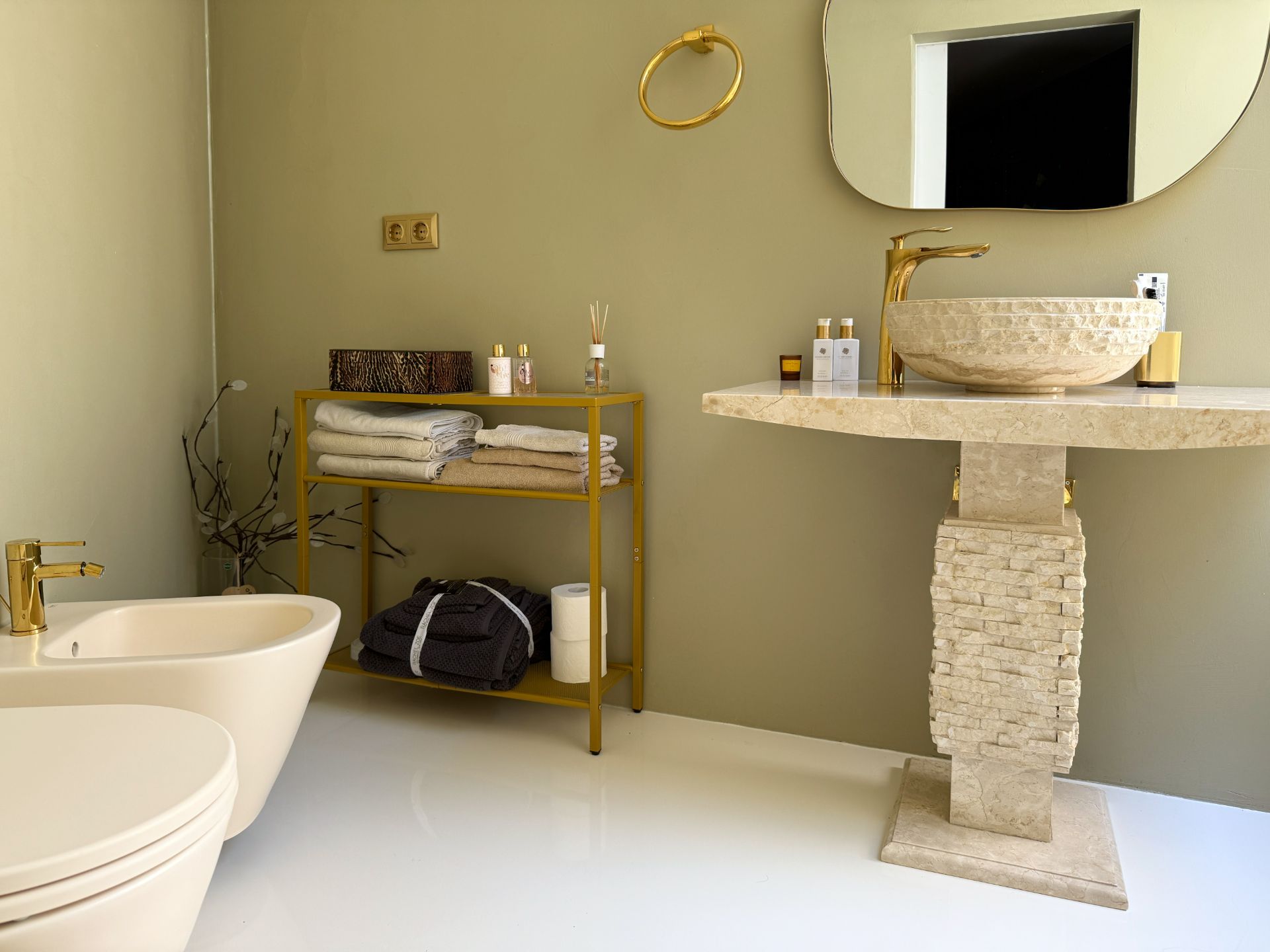 Modernes Badezimmer mit Waschbecken, Bidet, WC und Regal mit Handtüchern.