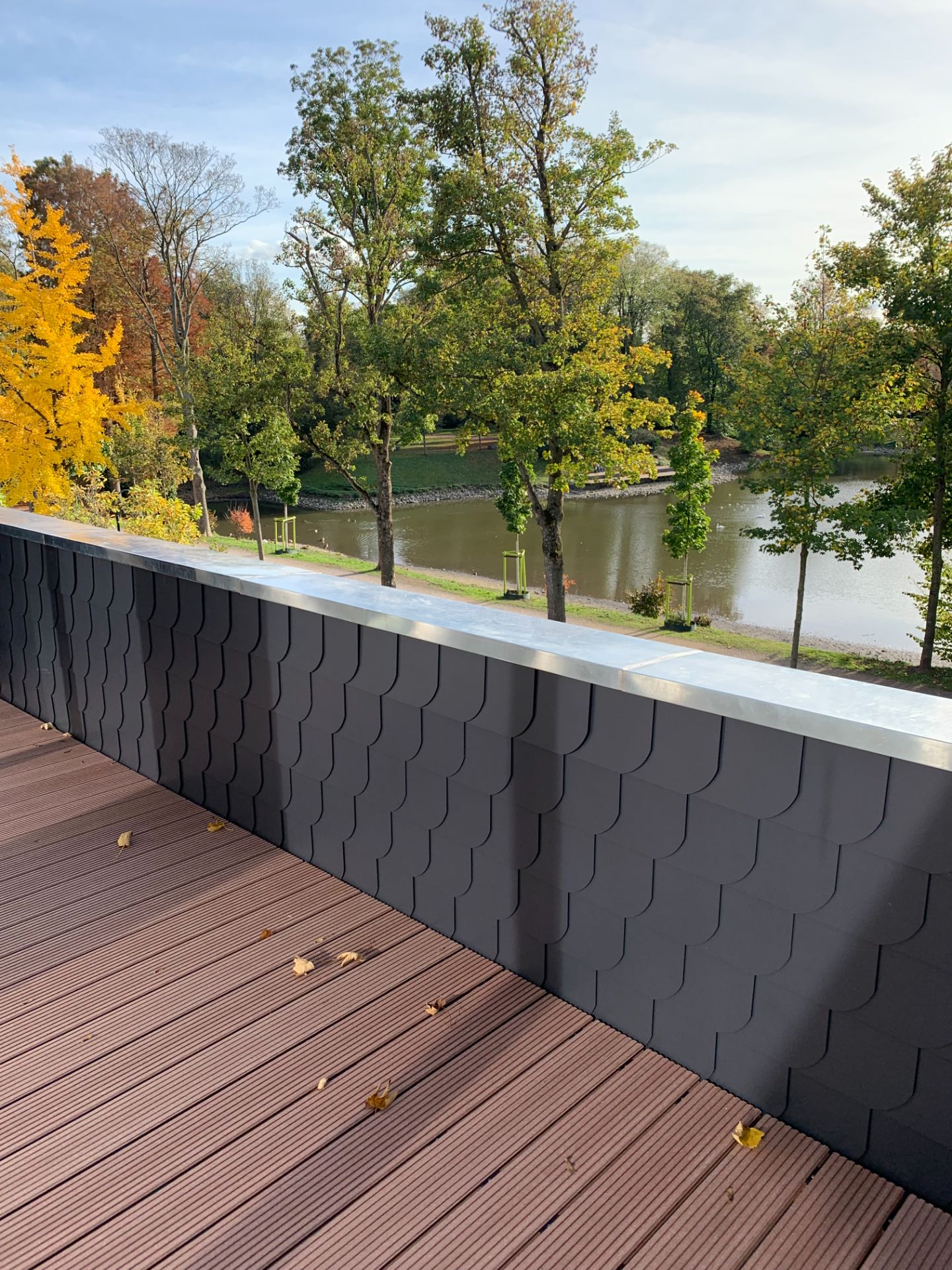 Balkon mit Holzfußboden, Blick auf Teich und Bäume im Grünen.