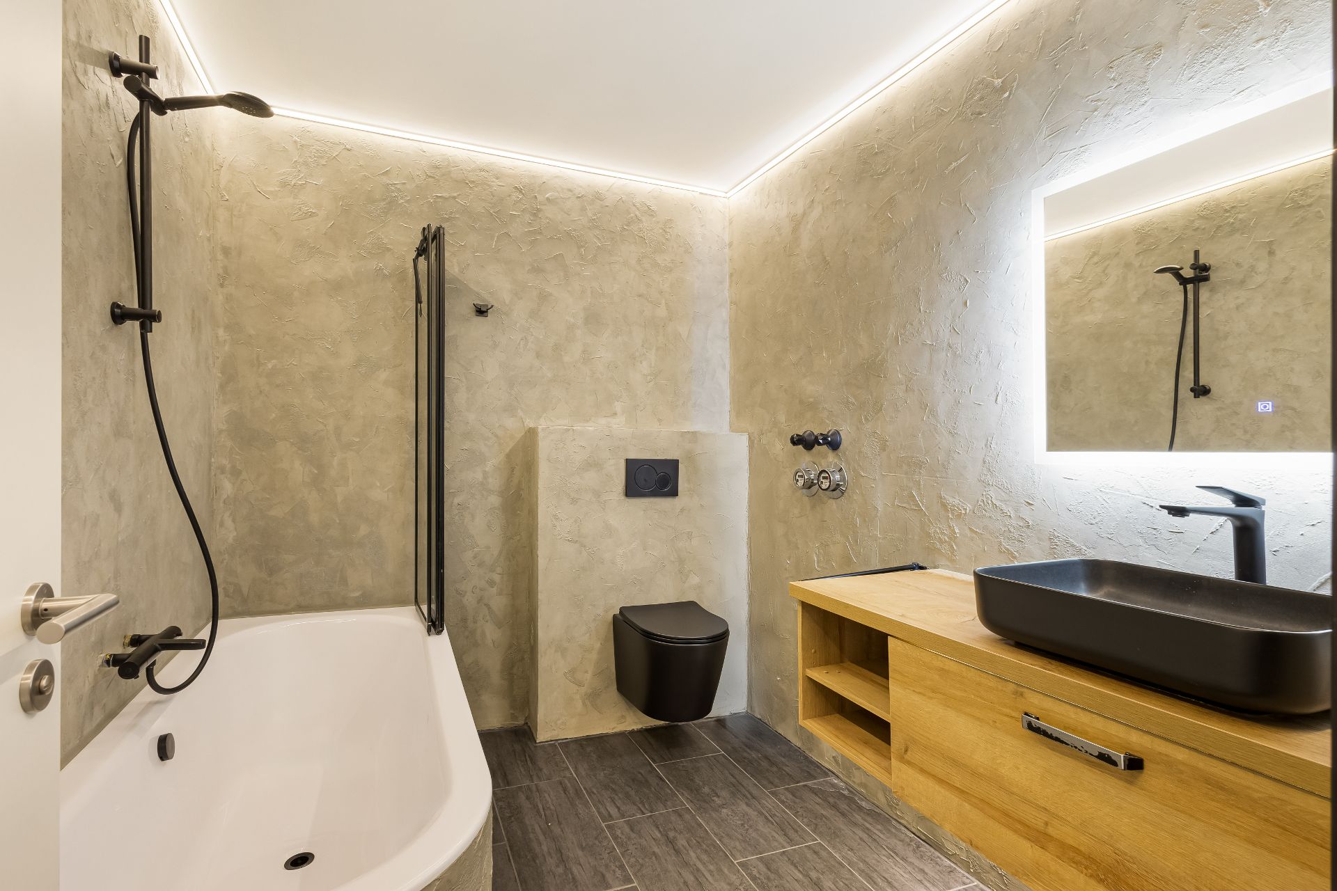 Modernes Badezimmer mit Badewanne, schwarzer Toilette und Holzwaschtisch mit Spiegel.