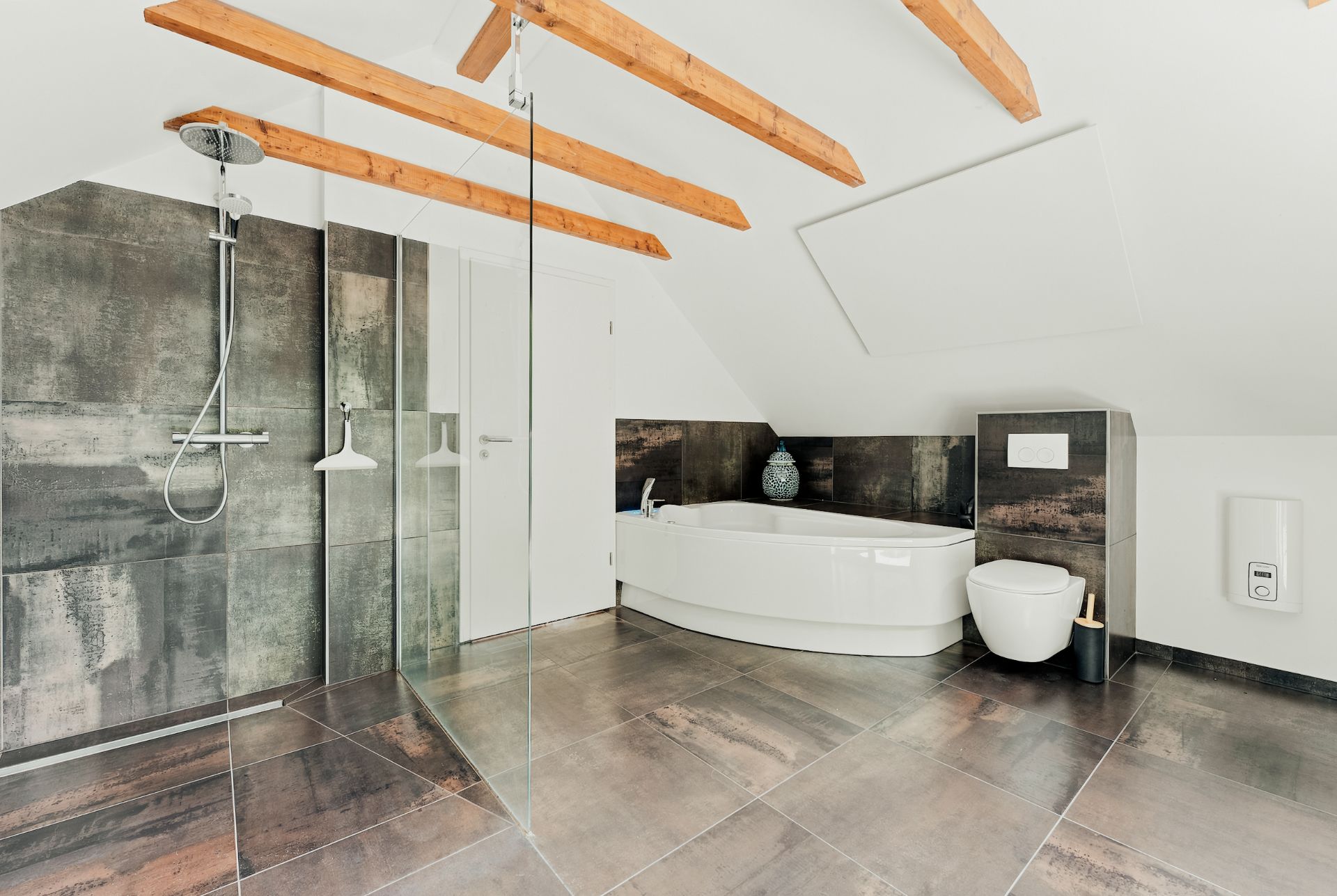 Helles Bad mit begehbarer Dusche, Badewanne, WC und sichtbaren Holzdeckenbalken.