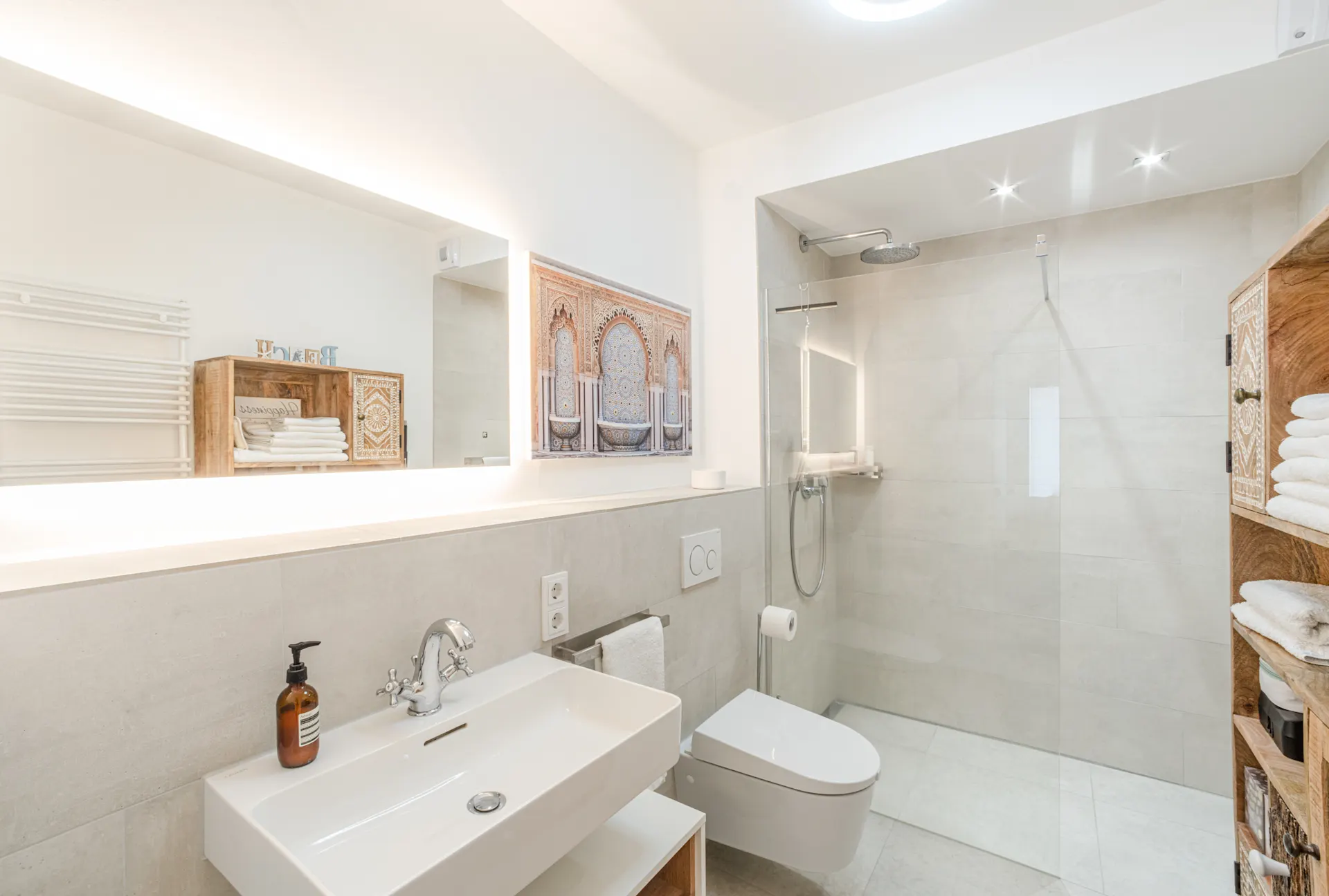 Helles, modernes Badezimmer mit Dusche, Waschbecken, WC und Regal mit Handtüchern.