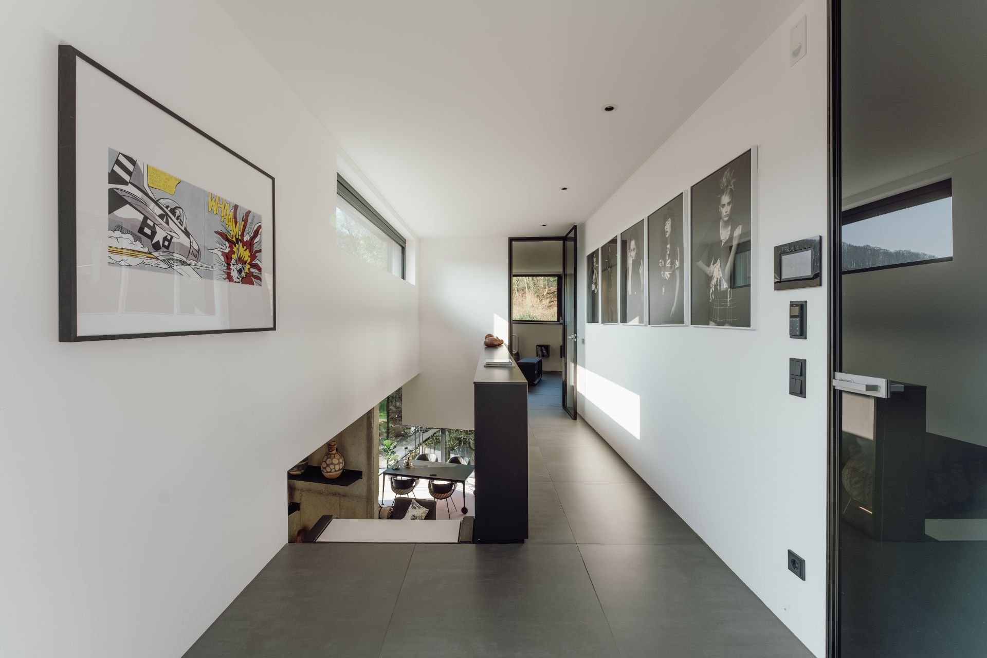 Moderner Flur mit großformatigen Fotos an der Wand und einem großen Fenster.