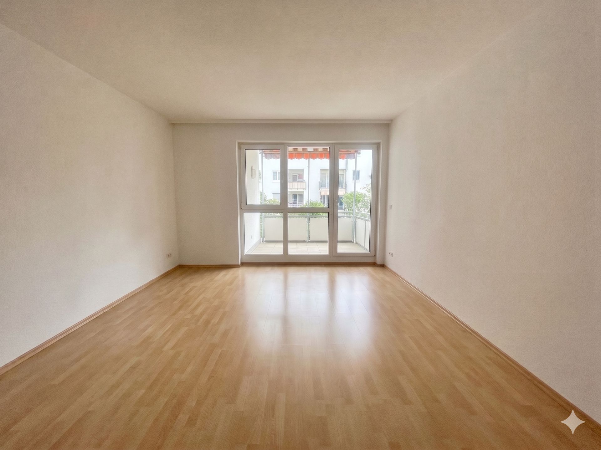 Leerer Raum mit hellem Laminatboden und großem Fenster zur Loggia.