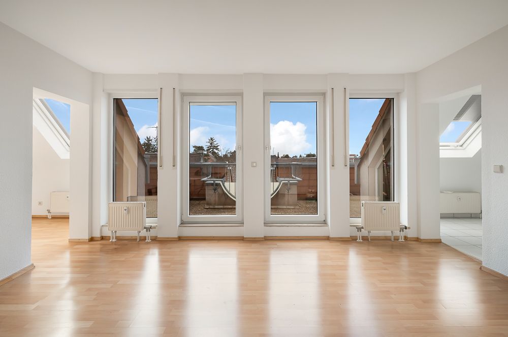 Helles Wohnzimmer mit Parkettboden und großen Fenstern, die auf eine Terrasse führen.