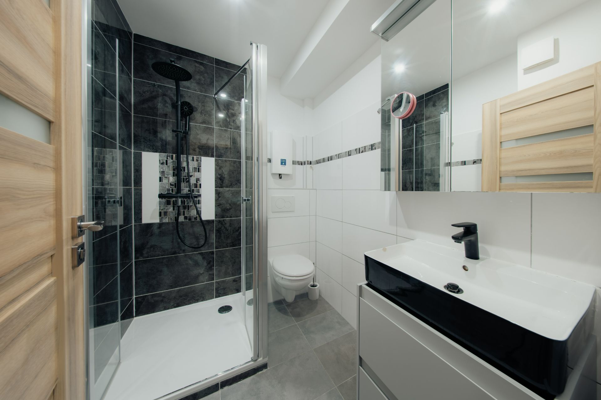 Modernes Badezimmer mit Dusche, Waschtisch, Spiegel und WC.
