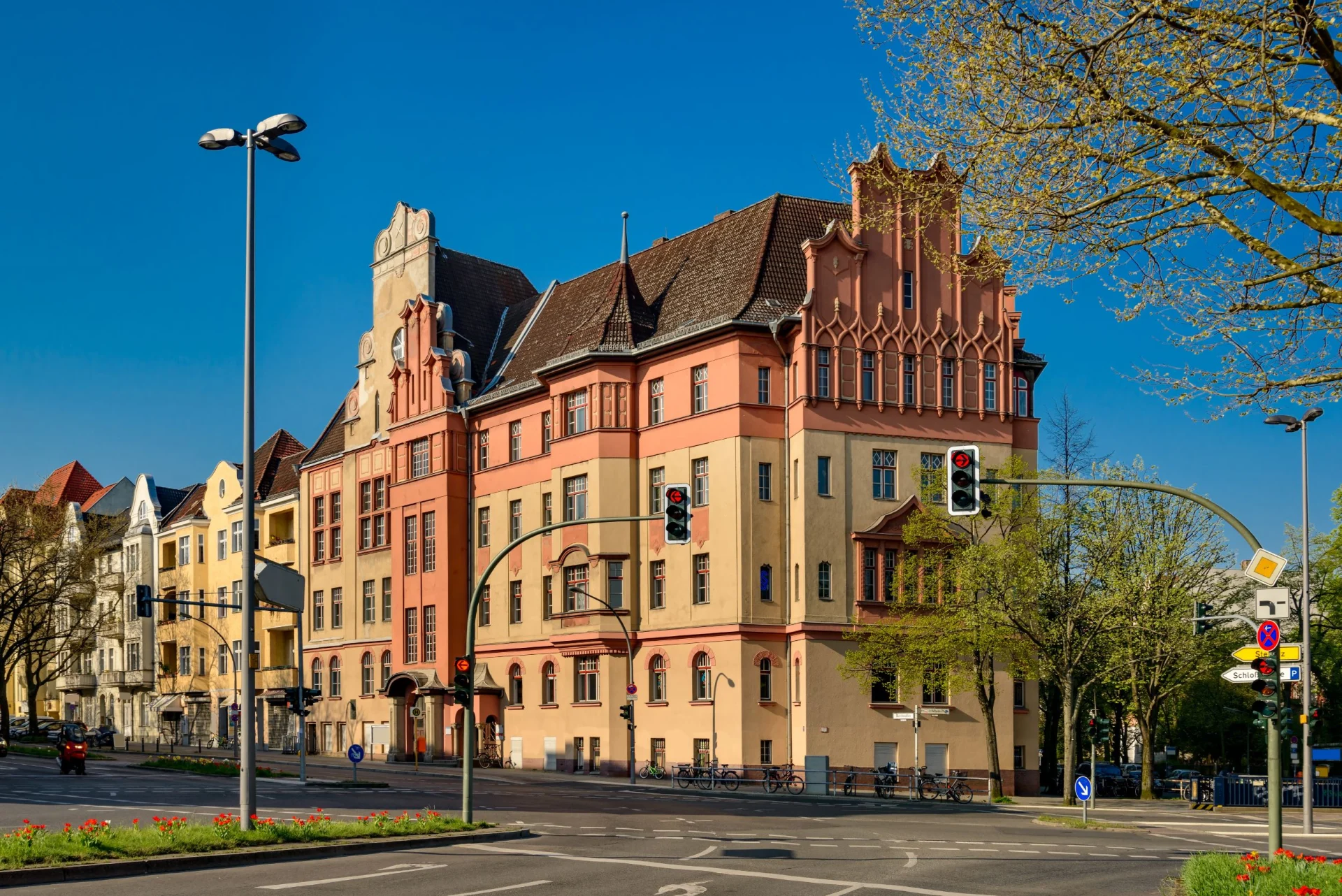 Mehrstöckiges Wohnhaus mit historische Fassade an einer Straßenecke bei Sonnenschein.