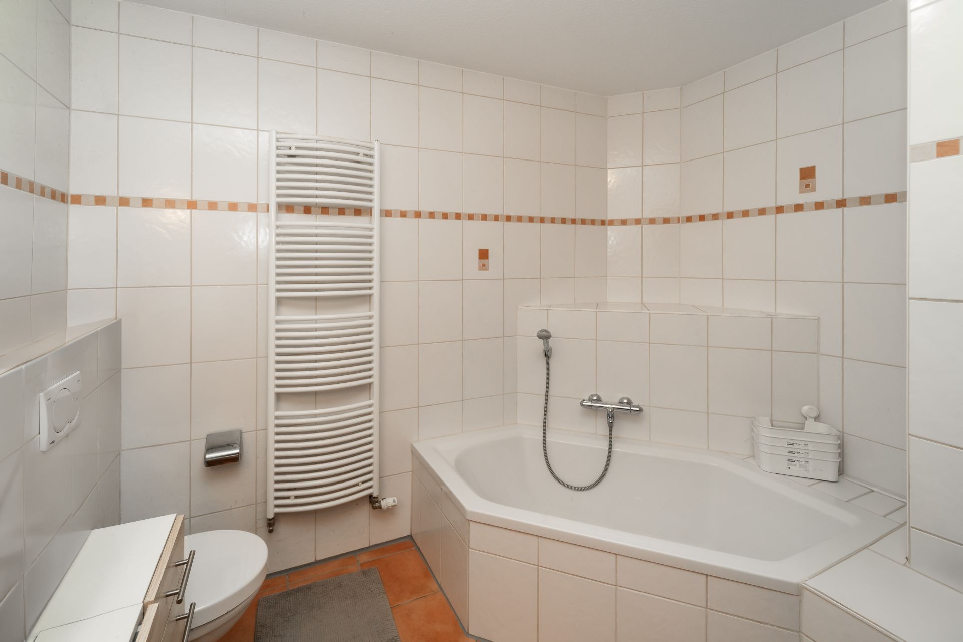 Modernes Badezimmer mit Eckbadewanne, Handtuchheizkörper und weißen Fliesen.