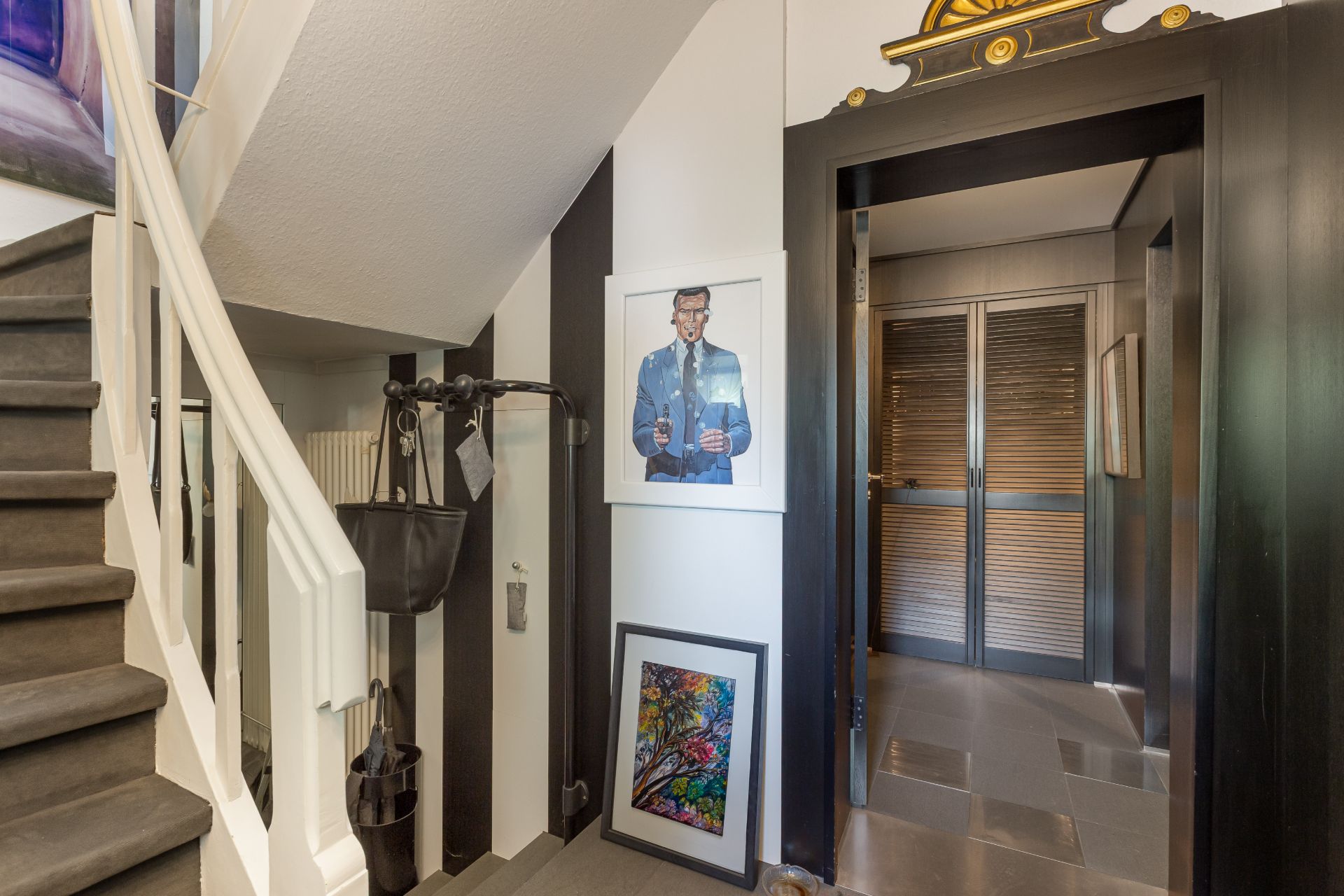 Treppenhaus mit Bildern an der Wand und einer offenen Tür zu einem weiteren Raum.
