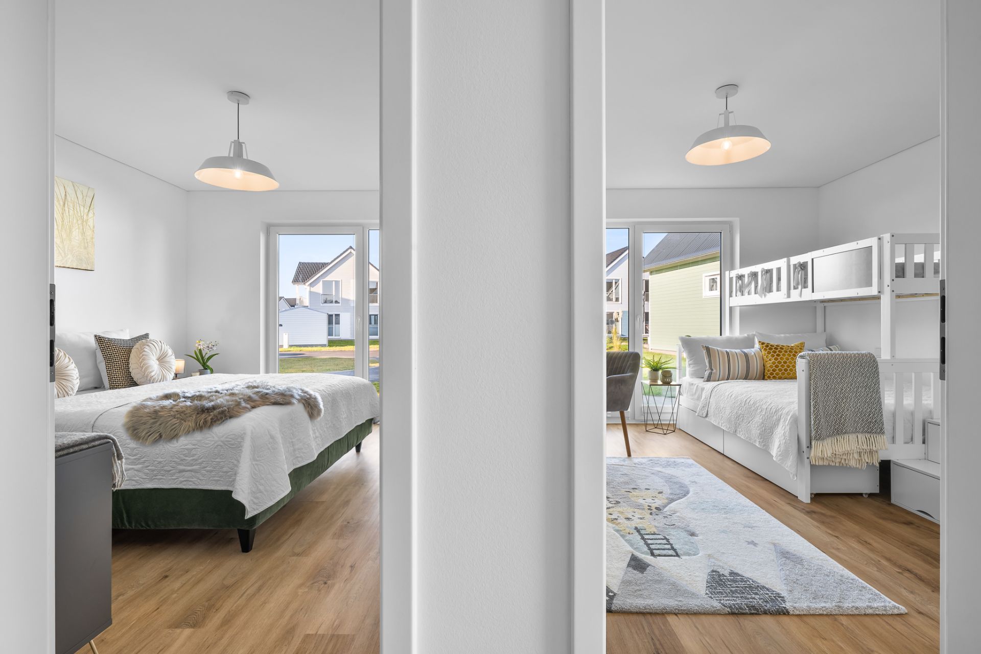 Blick durch einen Türrahmen auf zwei modern eingerichtete Schlafzimmer mit großen Fenstern.
