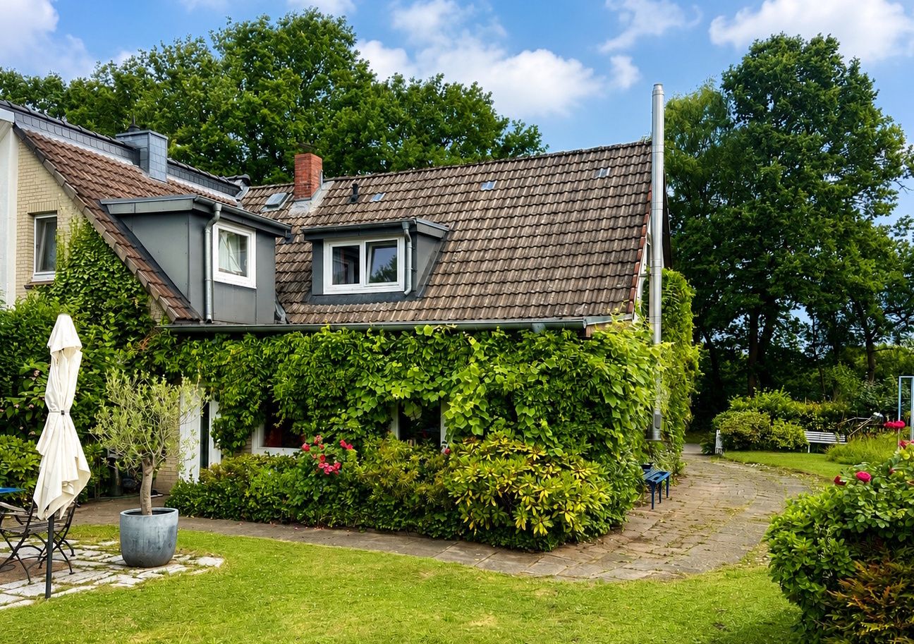 Wohnhaus mit begrüntem Dach, Terrasse und Garten mit Sträuchern und Rasen.