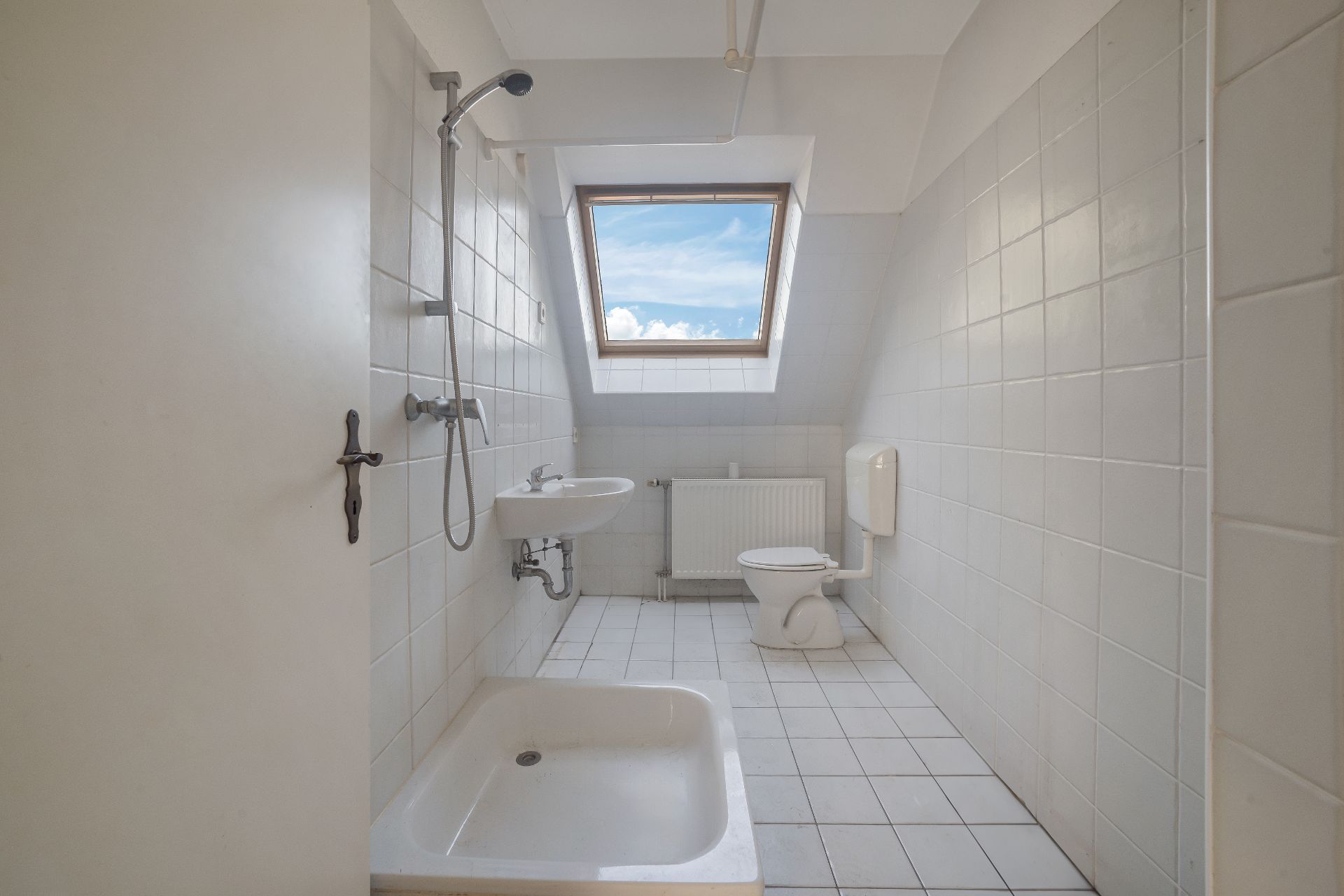 Helles Badezimmer mit Dusche, WC, Waschbecken und Fenster unter der Dachschräge.