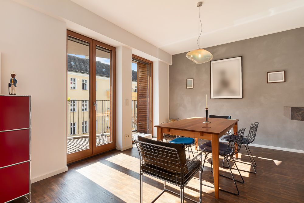 Helles Esszimmer mit Holztisch, vier Stühlen und Zugang zum Balkon, große Fenster lassen viel Licht herein.