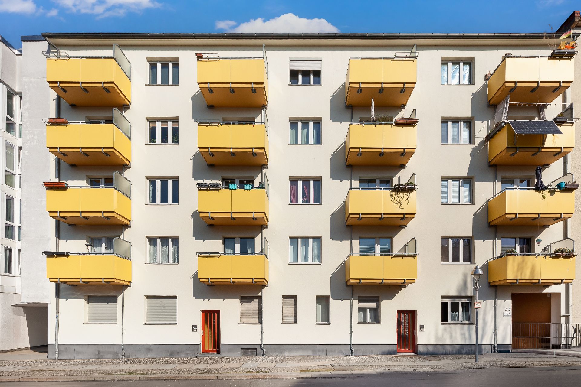 Wohnhaus mit gelben Balkonen und mehreren Fenstern an der Fassade.