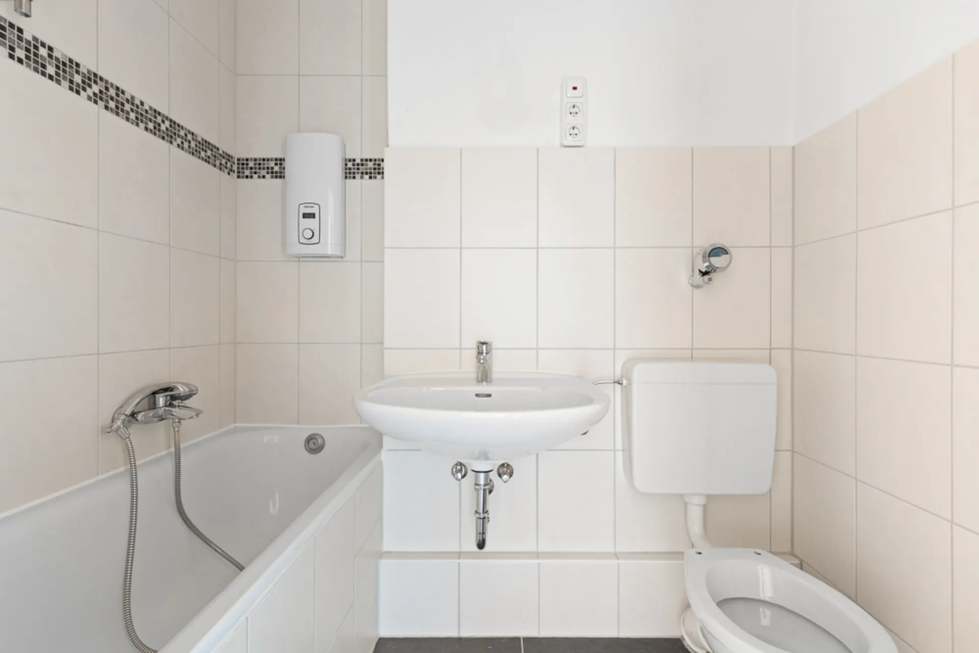 Helles Badezimmer mit Badewanne, Waschbecken und Toilette, weiße Fliesen an den Wänden.