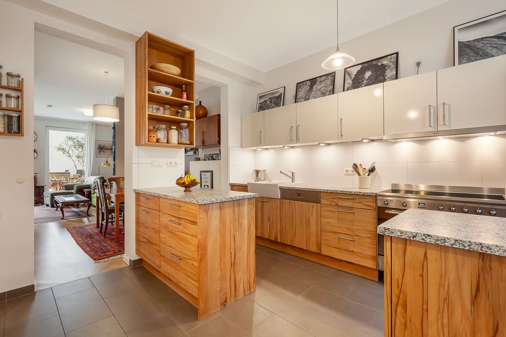 Moderne Küche mit Holzschränken, Kücheninsel und Blick ins Wohnzimmer mit Esstisch.