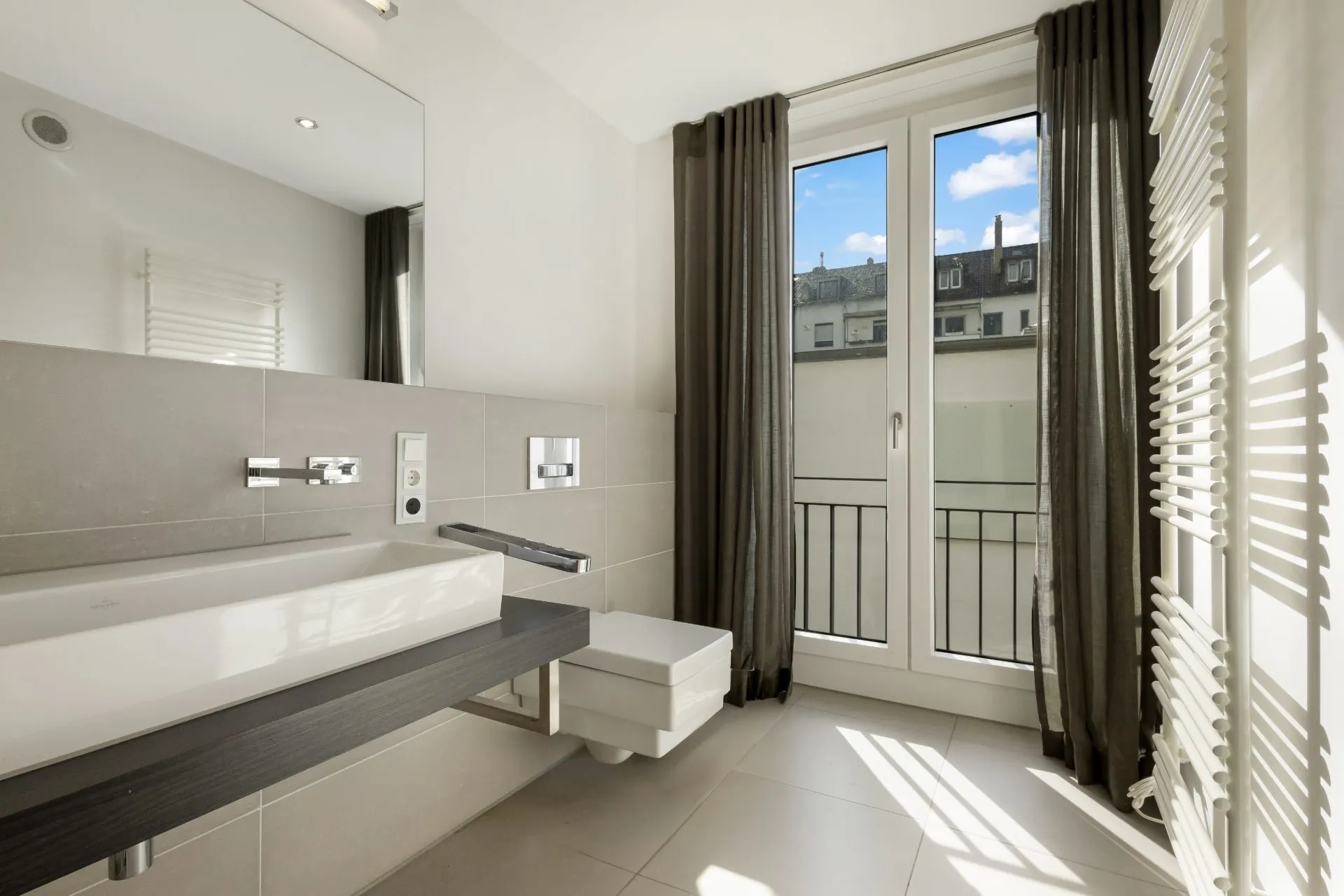 Modernes Badezimmer mit großem Fenster, Waschbecken, Spiegel und Heizkörper.