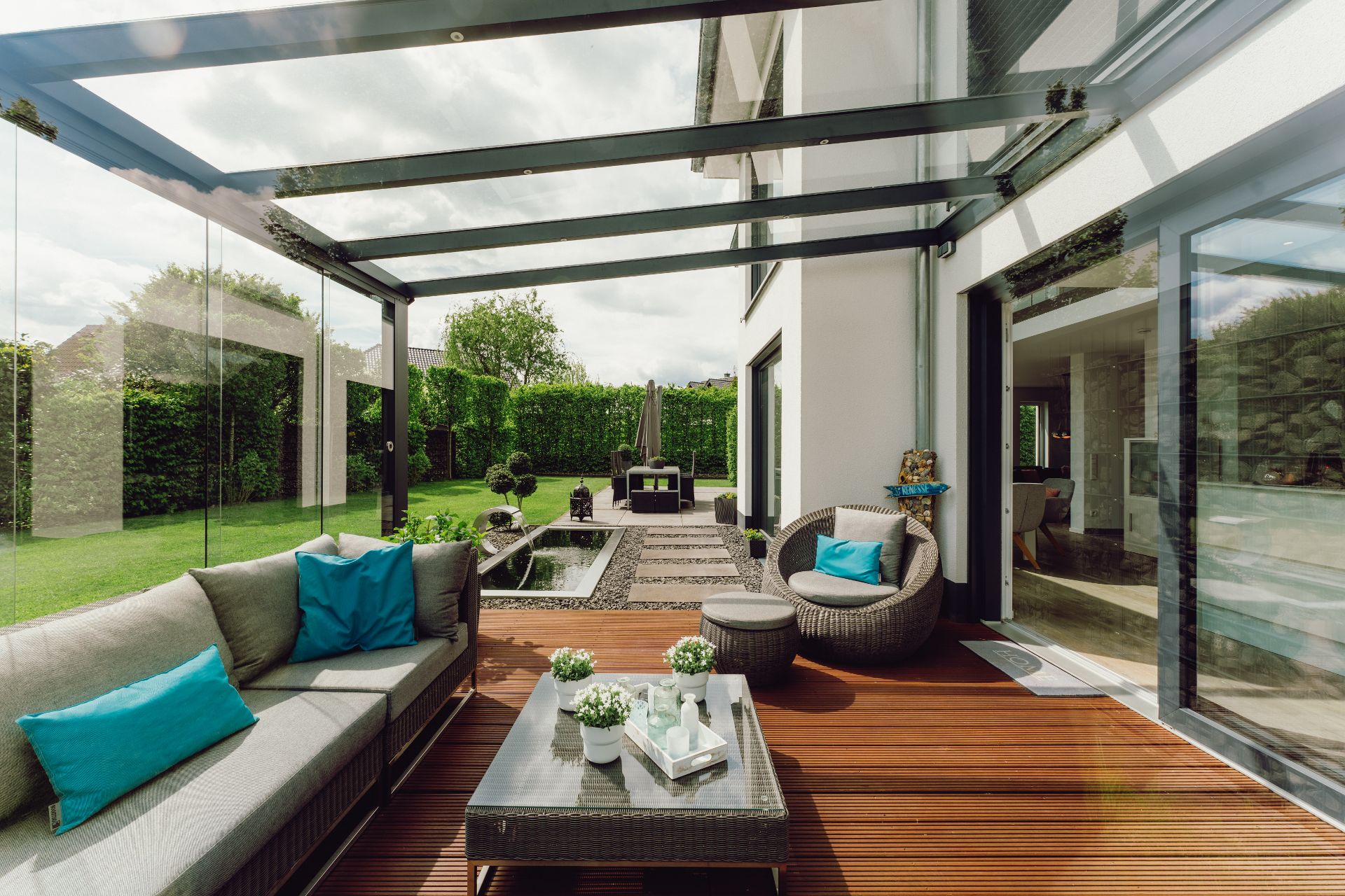 Moderne Terrasse mit Glasdach, gemütlicher Sitzgruppe und Blick auf den Garten.