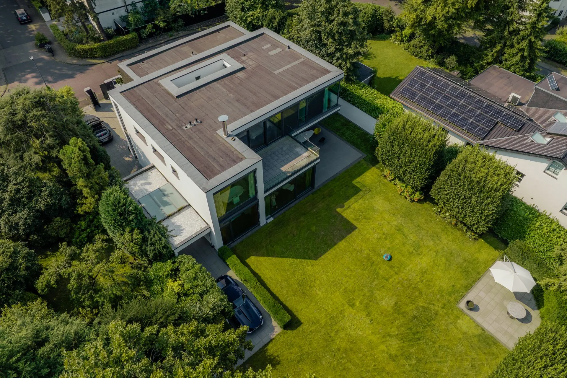 Luftaufnahme eines modernen Wohnhauses mit Flachdach und großem Garten.