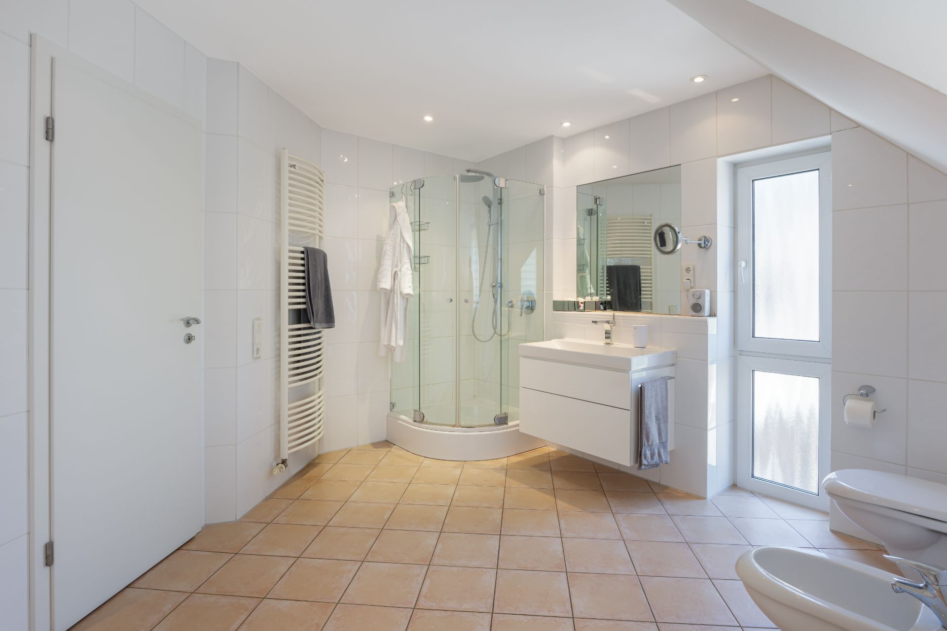 Helles Badezimmer mit Dusche, Waschbecken, Bidet, WC und großem Spiegel.