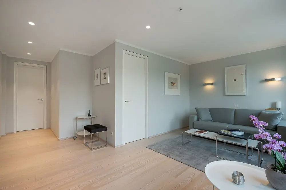 Modernes Wohnzimmer mit grauem Sofa, Couchtisch, hellen Wänden und Holzfußboden.
