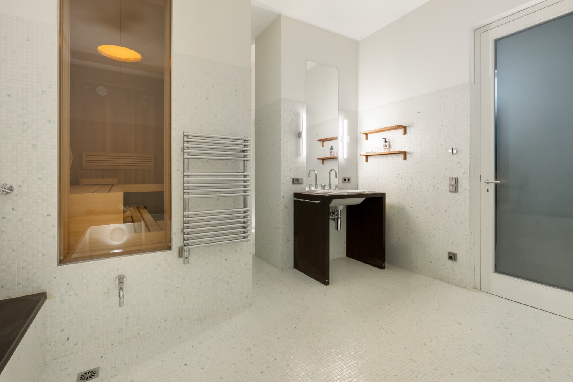 Modernes Badezimmer mit Sauna, Handtuchheizkörper, Waschbecken und Spiegel.