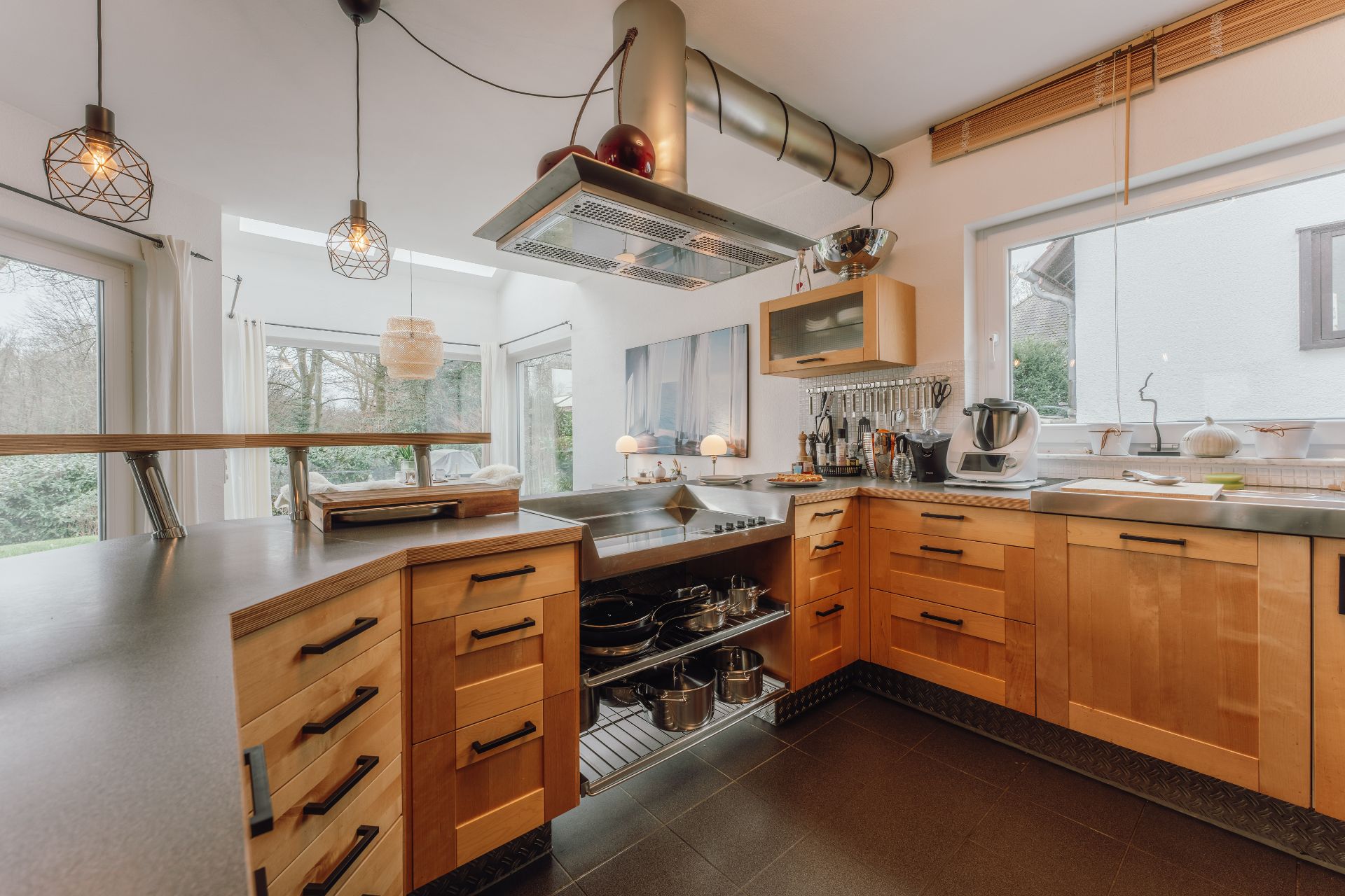 Moderne Küche mit Holzschränken, Küchengeräten und großem Fenster, Blick auf den Garten.